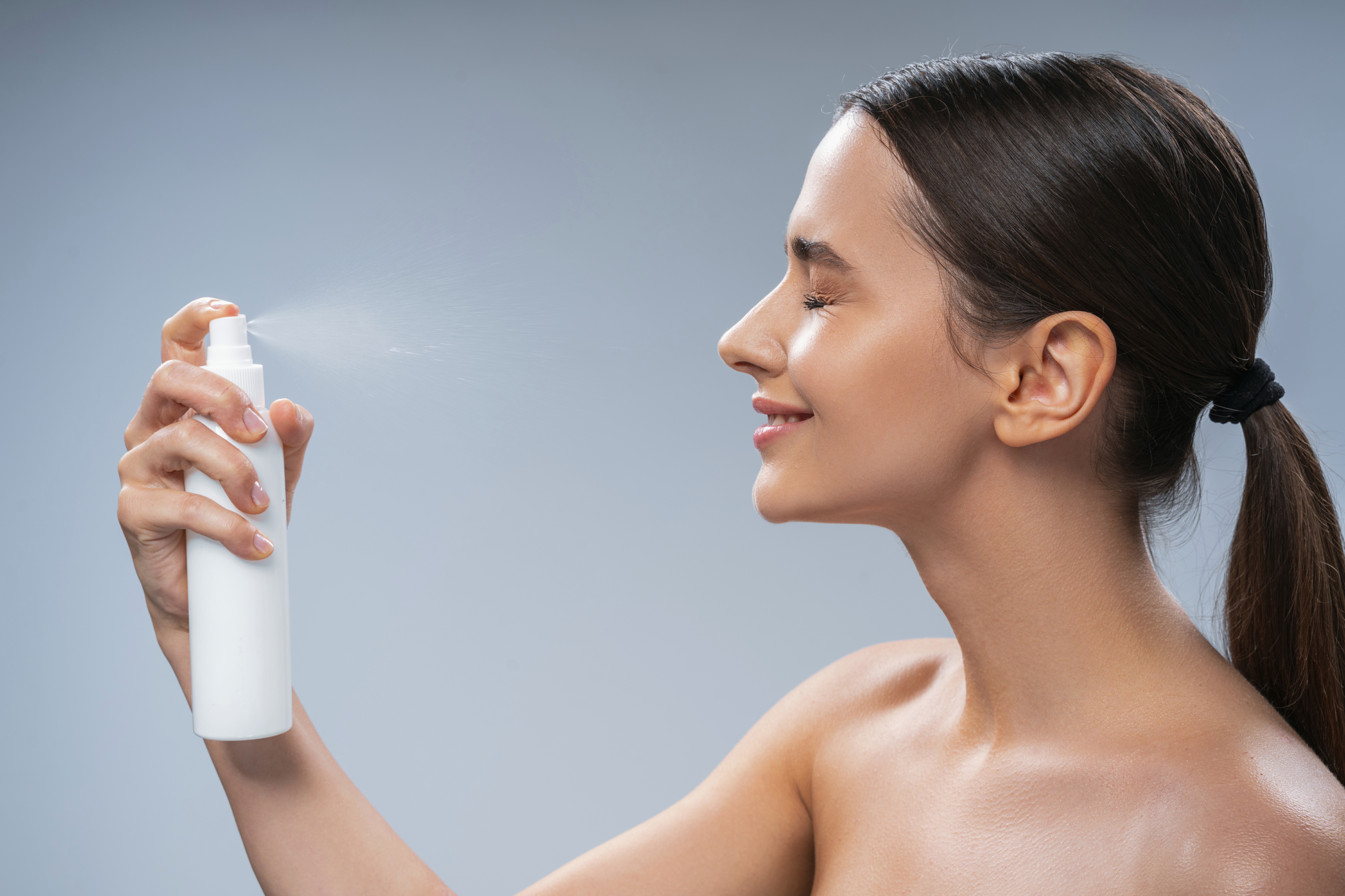 Woman applying facial spray. | Source: Getty Images