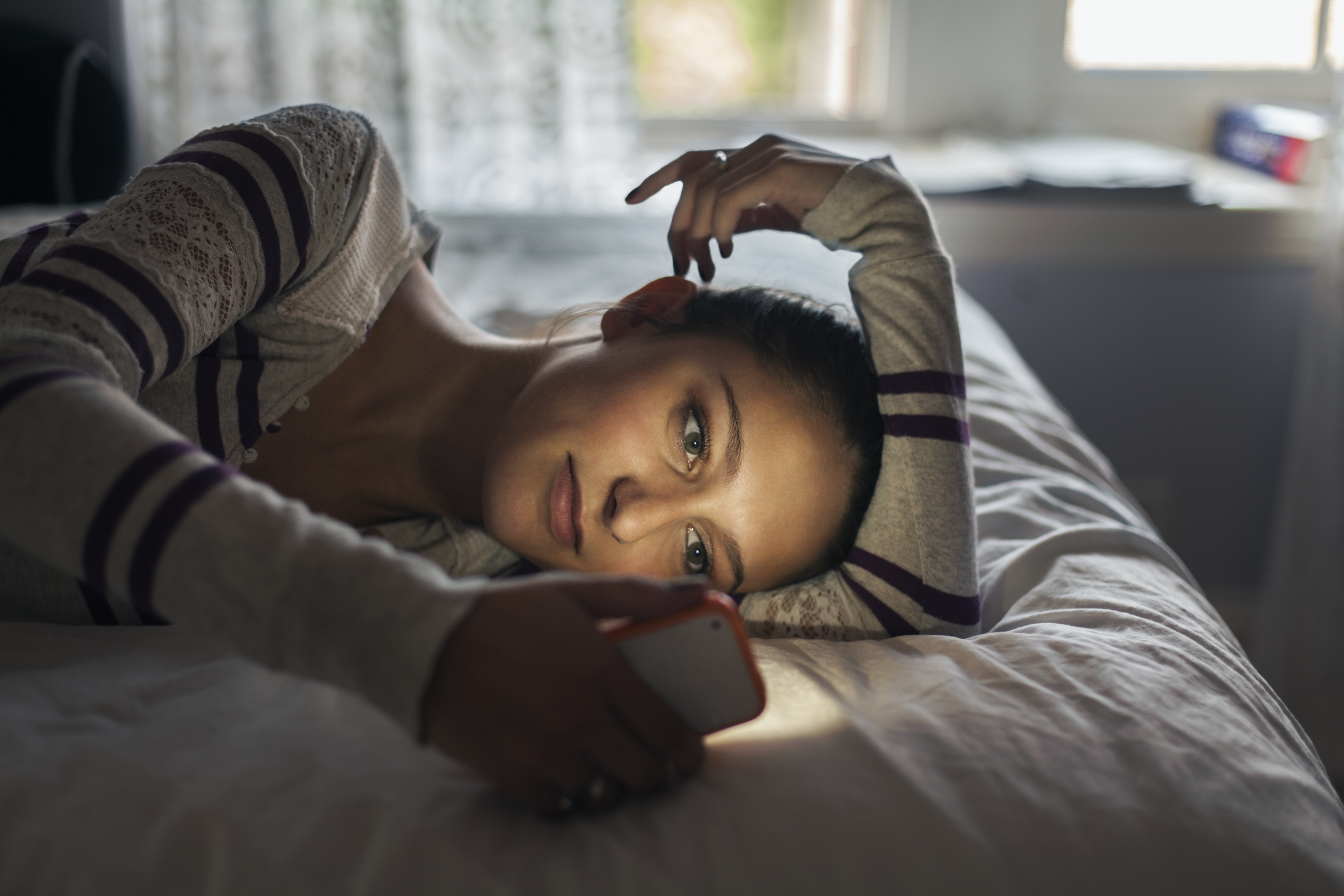 A girl laying on her bed and using her phone. | Source: Getty Images