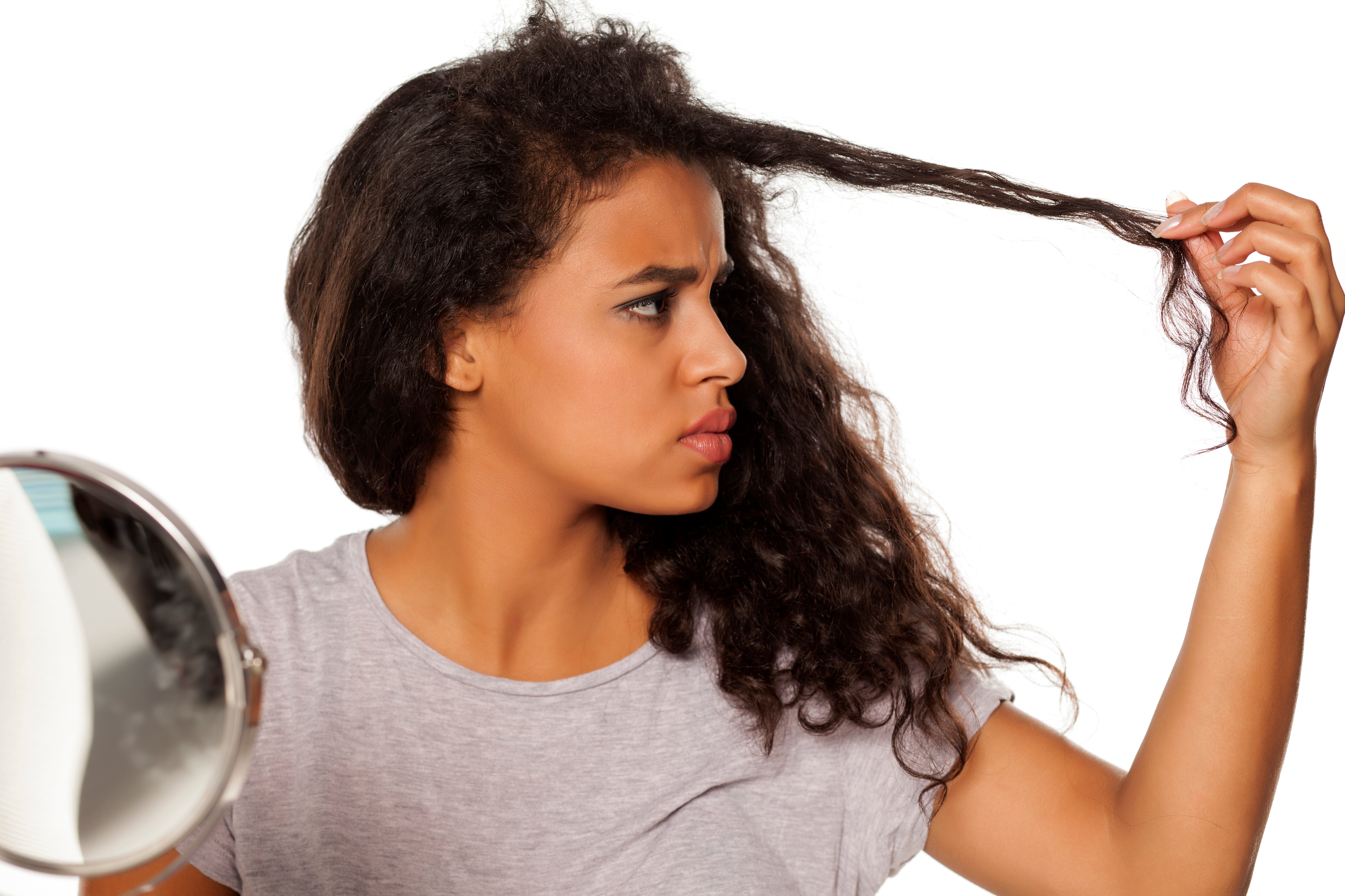 A woman worryingly examining a section of her hair | Source: Shutterstock
