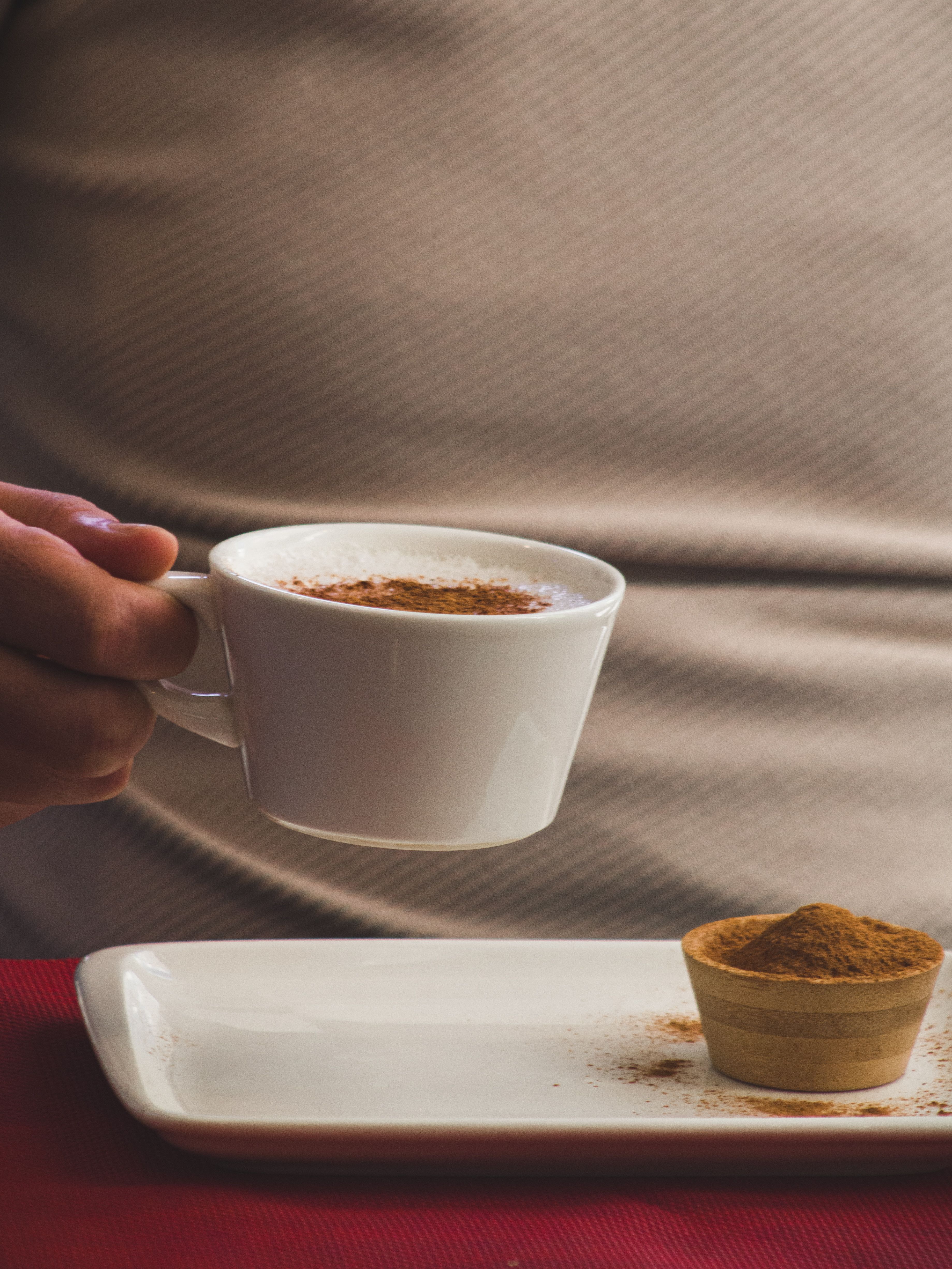 A person's hand holding a cup of coffee with cinnamon | Source: Pexels