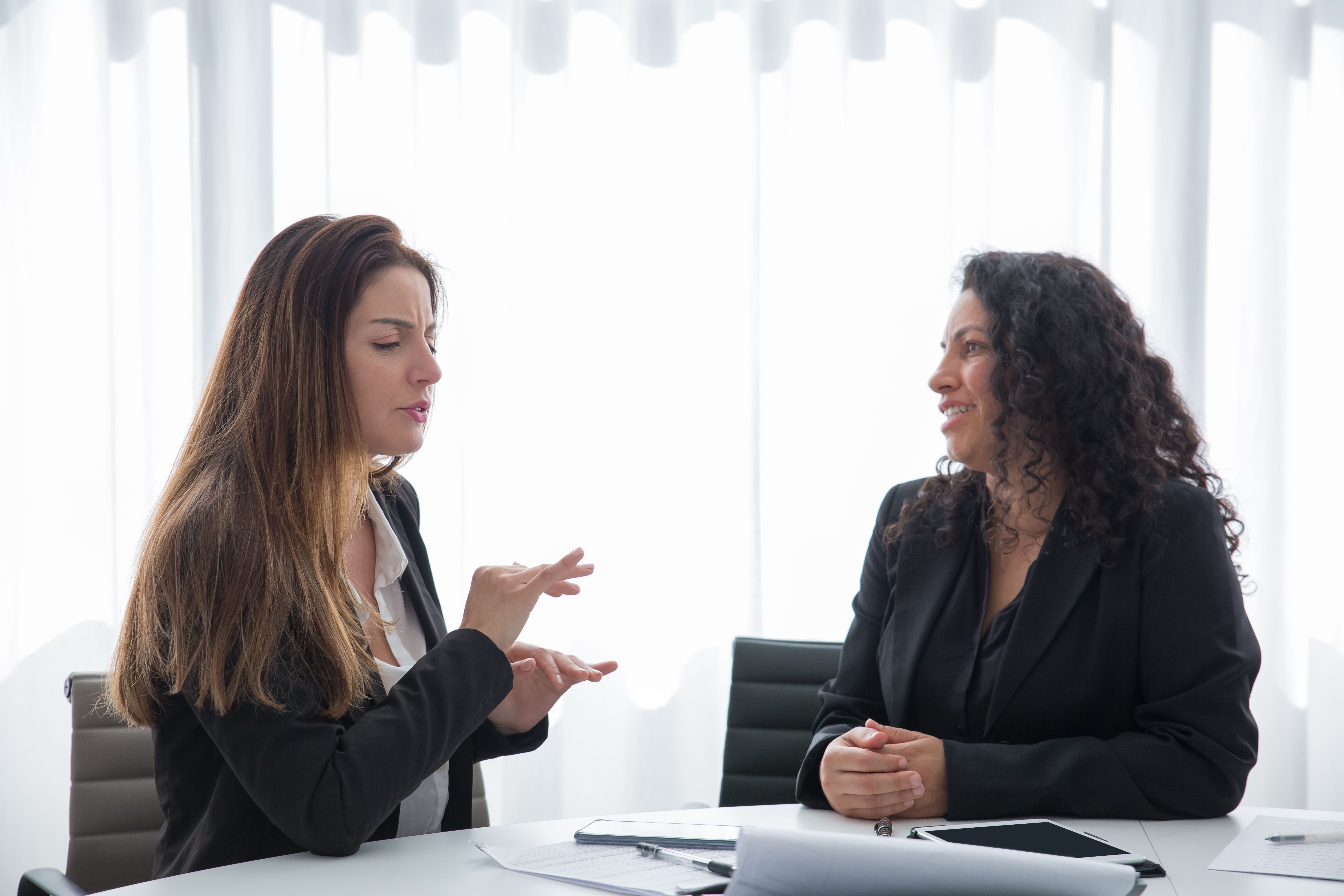 A woman listening while another woman explains in an office meeting | Source: Pexels