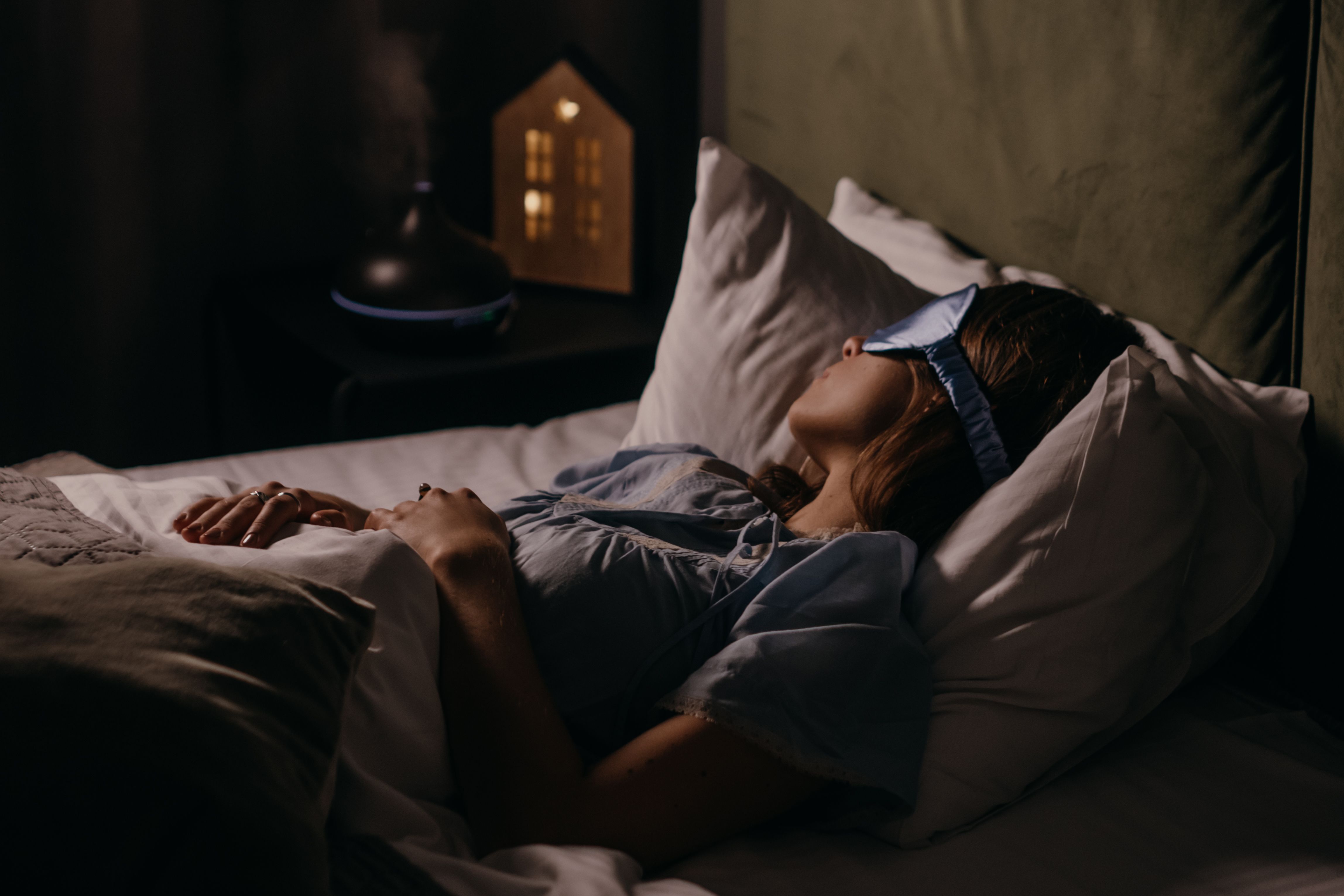 A woman sleeping at night with an eye mask and light shining through the window | Source: Pexels
