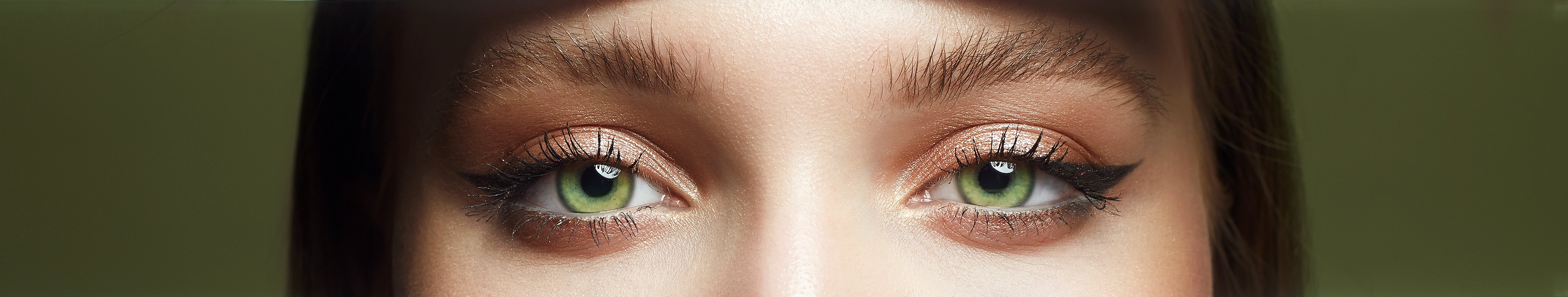 A cropped photo of a woman with green eyes wearing golden-toned eyeshadow in her makeup | Source: Shutterstock