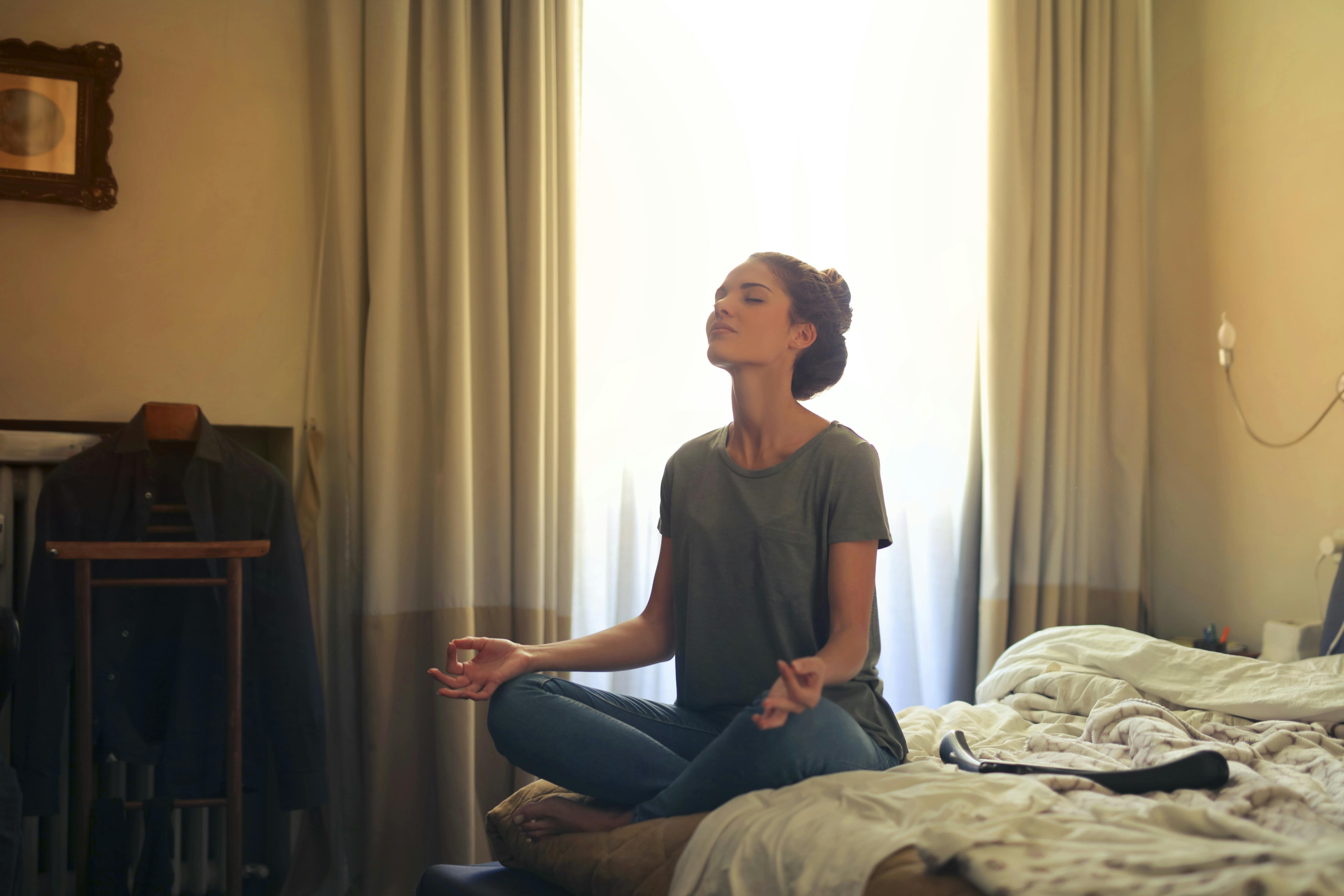 A woman meditates inside her bedroom. | Source: Pexels
