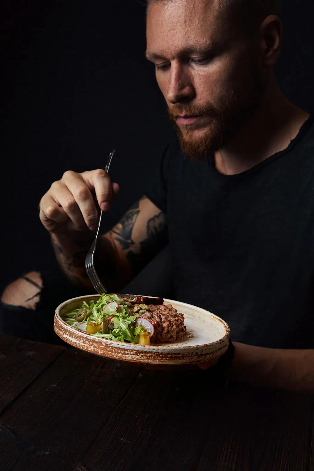 Um homem comendo carne com vegetais | Fonte: Pexels