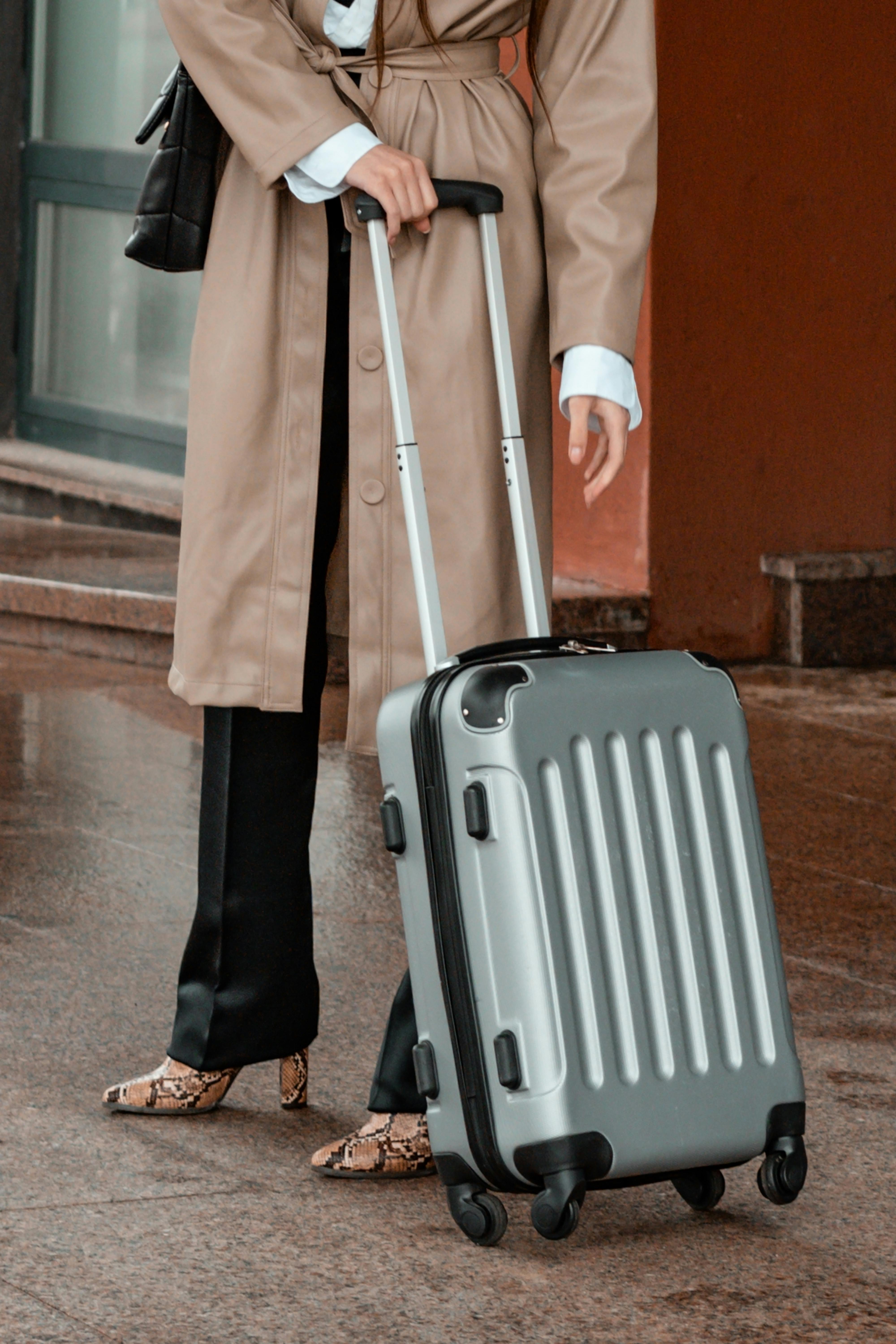 A woman standing with a suitcase | Source: Pexels