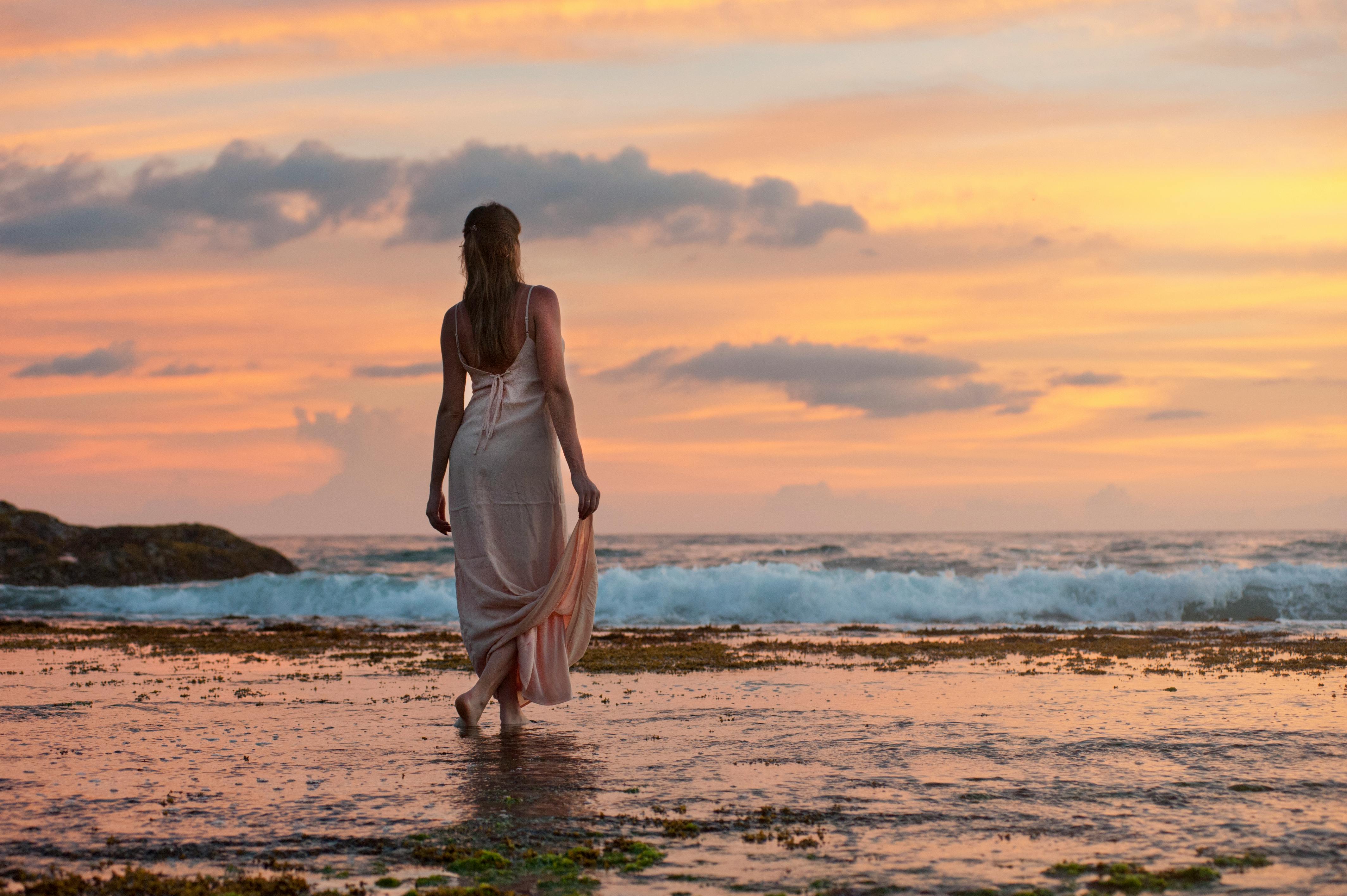 Woman standing on sand near shoreline | Source: Pexels