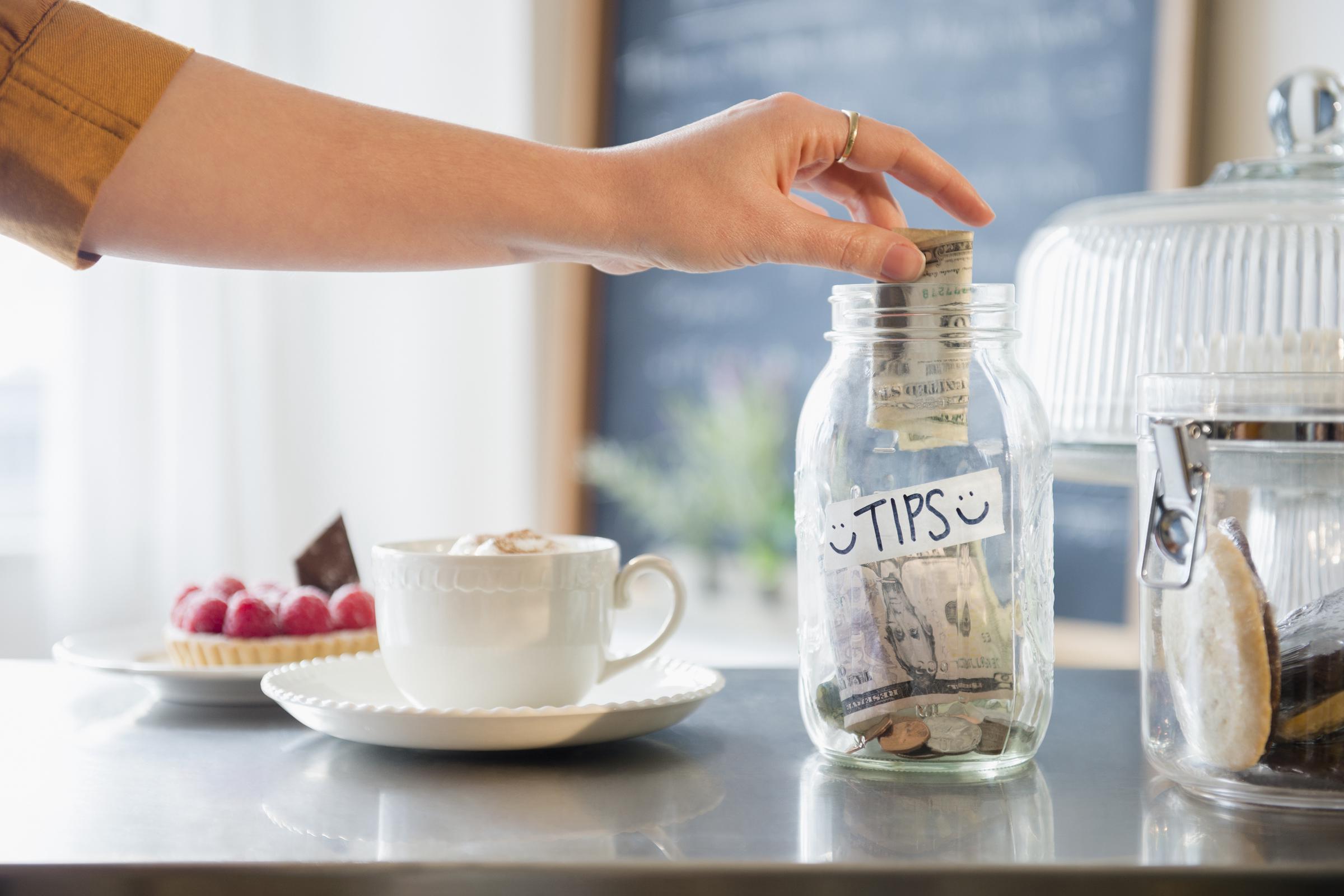A woman putting money inside a tip jar | Source: Getty Images