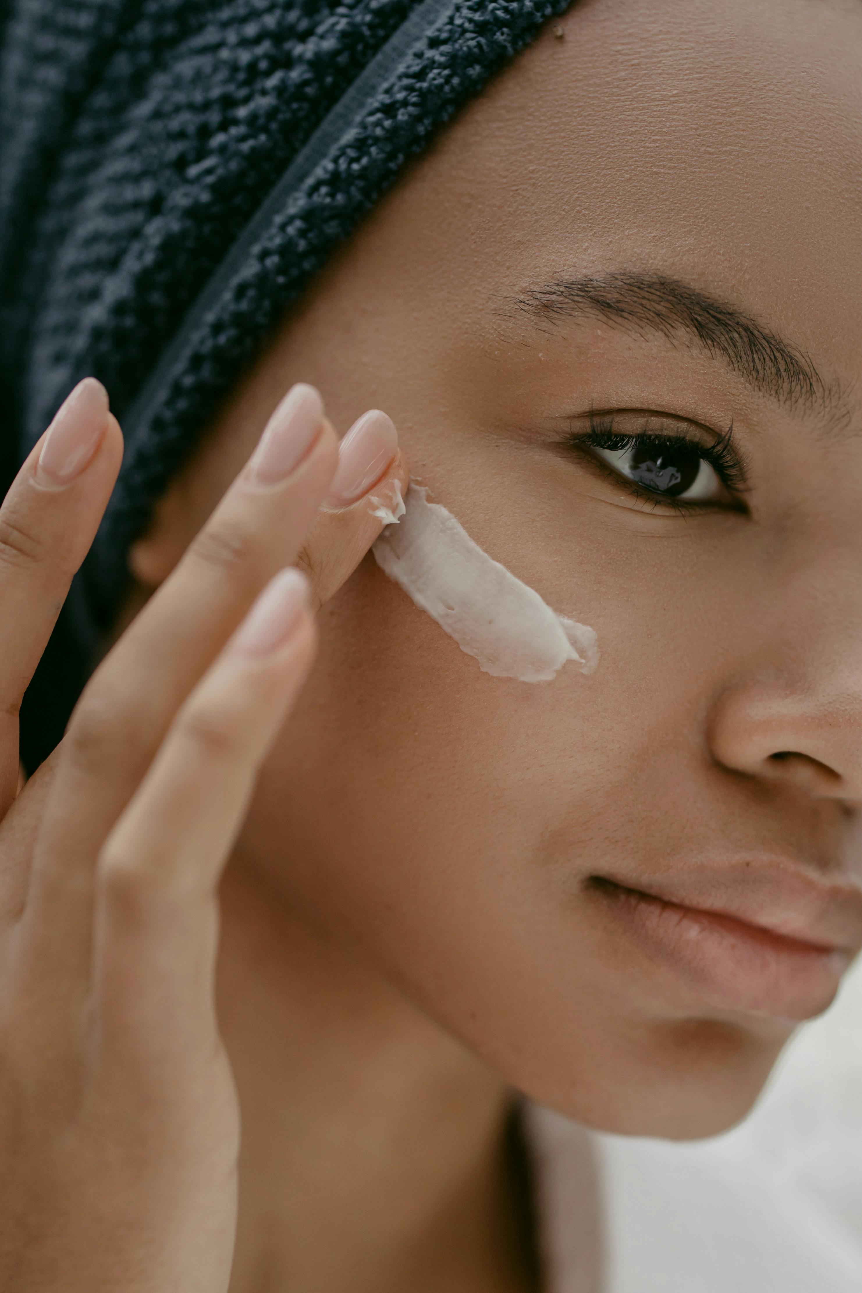 A woman applying face cream on her cheeks | Source: Pexels