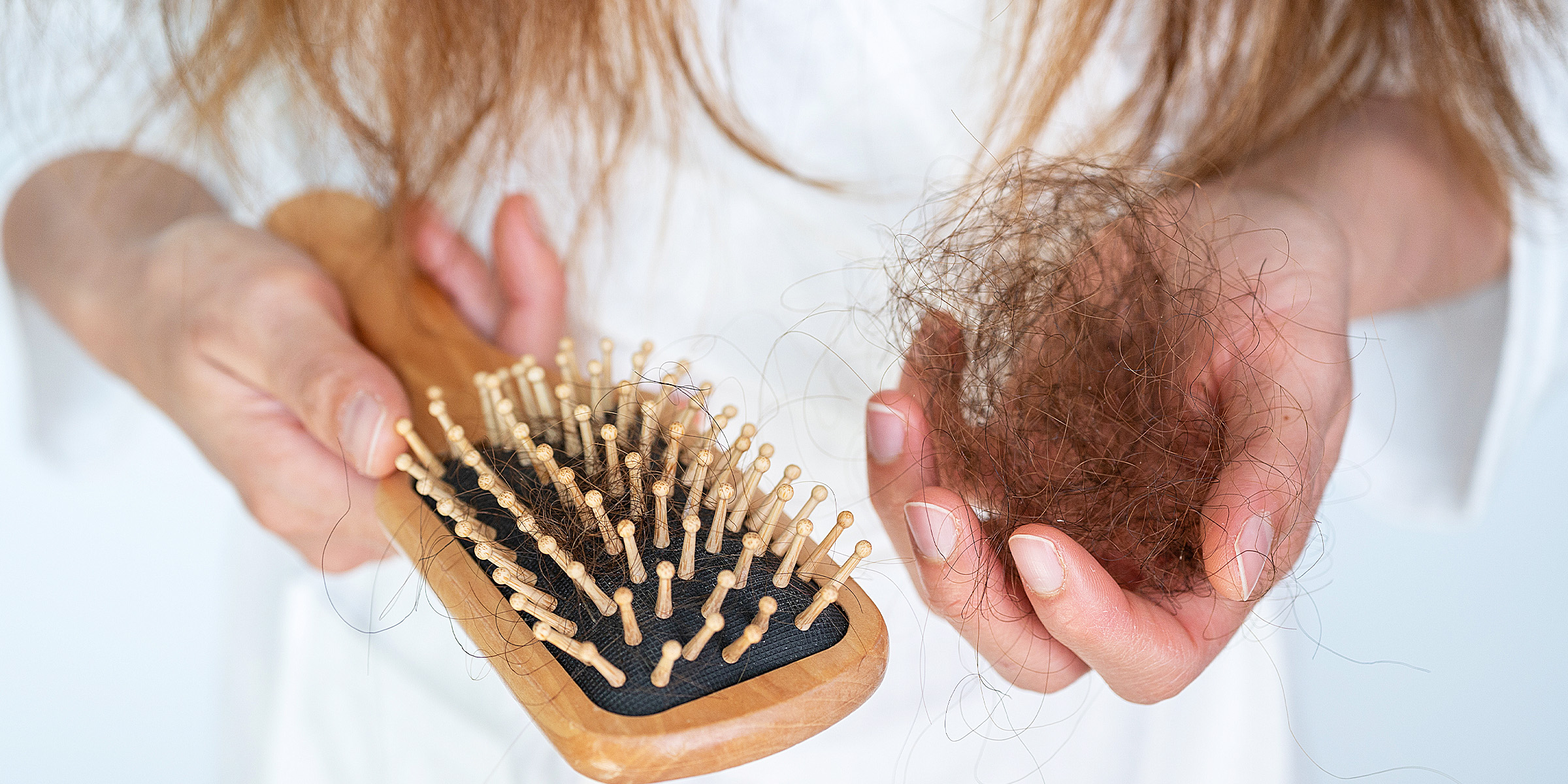 A woman holding a brush and a large clump of hair | Source: Getty Images