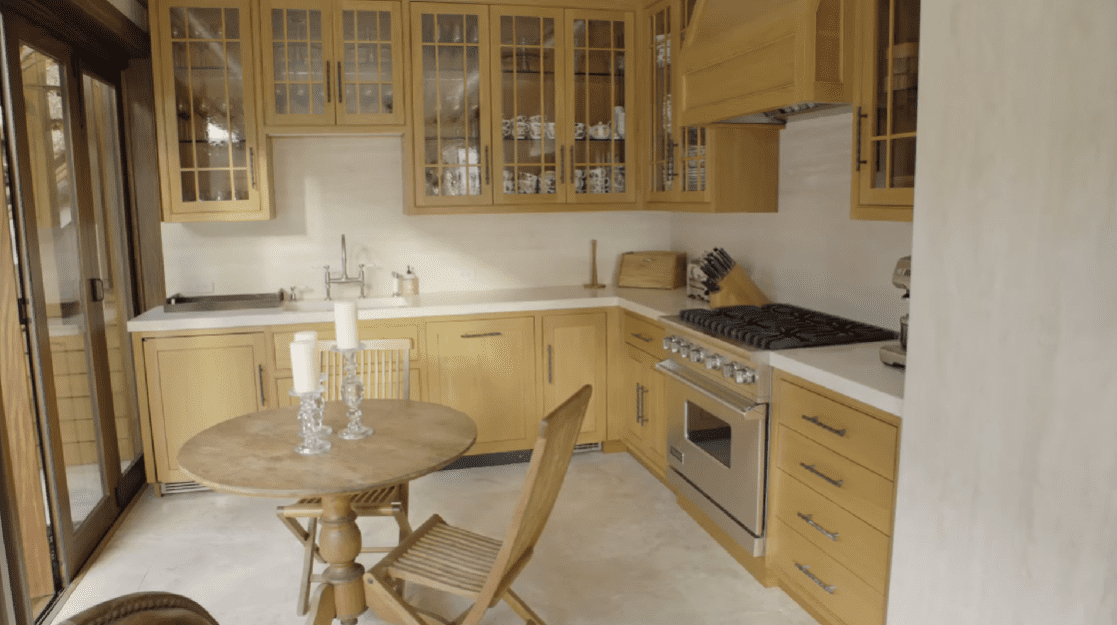 Pierce Brosnan and Keely Smith's limited space kitchen with wooden cabinets. / Source: YouTube/@ArchitecturalDigestIndia