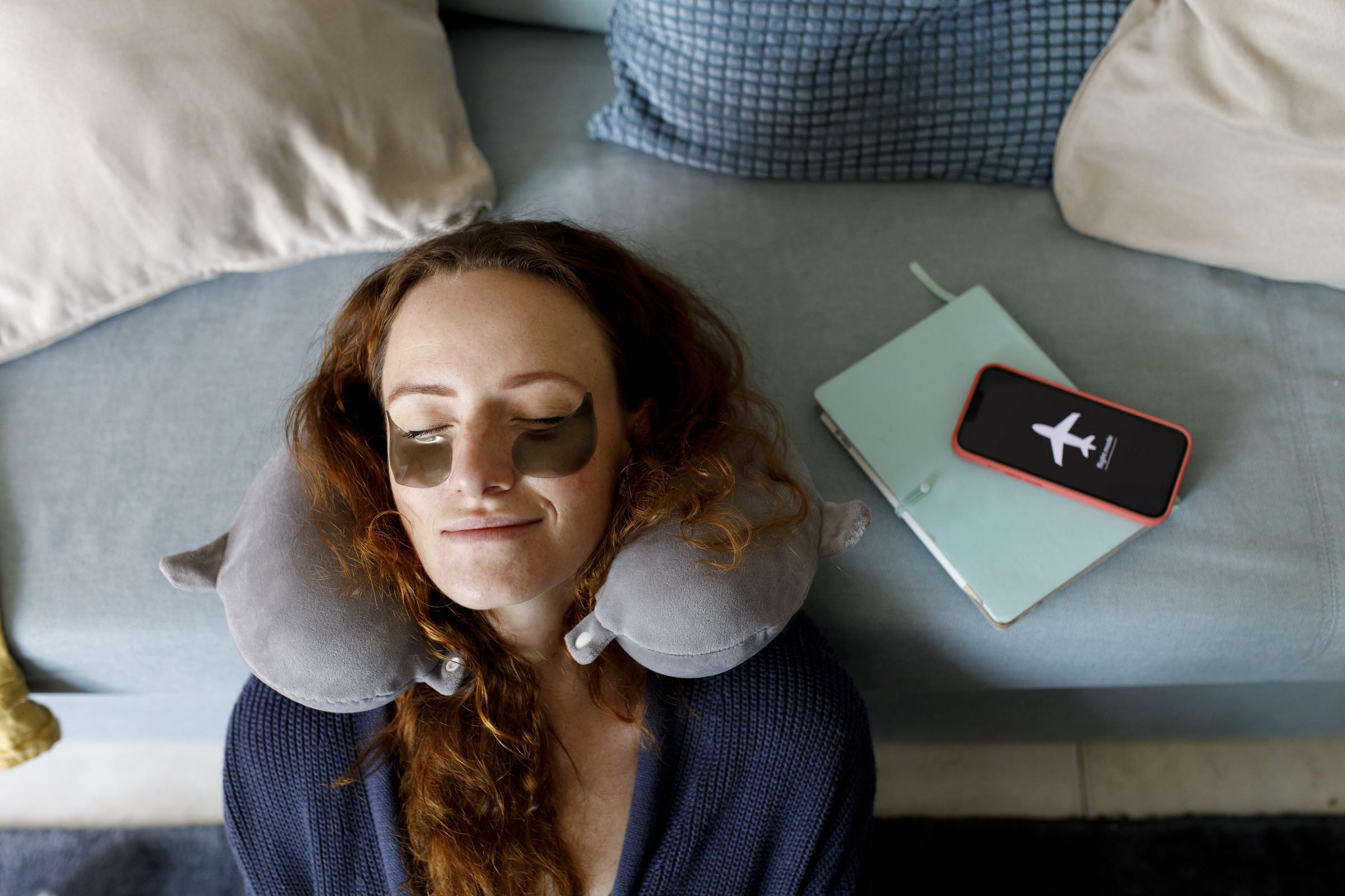 A woman leaning her head on a sofa with her smart phone on airplane mode | Source: Getty Images