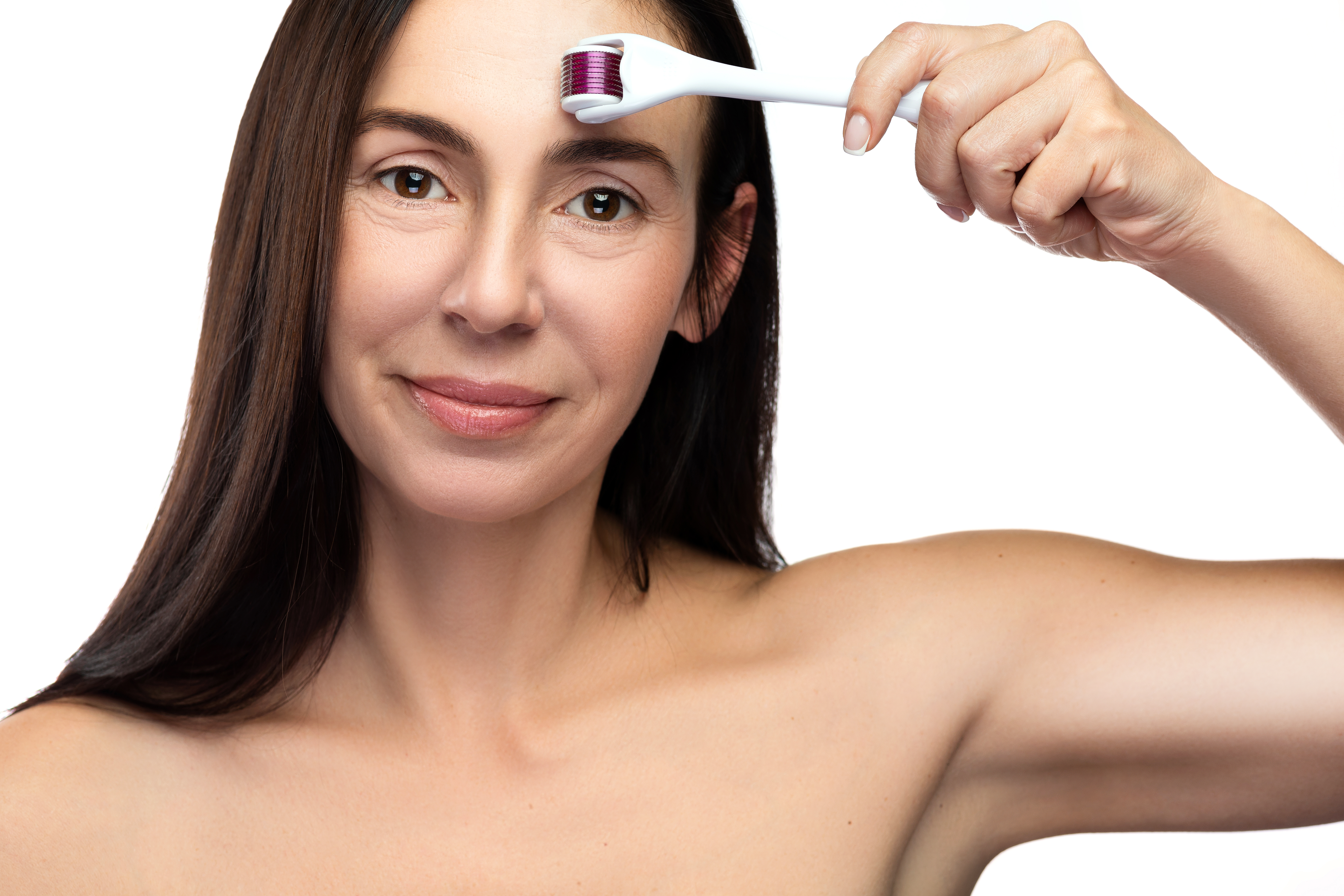 A woman dermarolling the areas around her eyebrows | Source: Getty Images