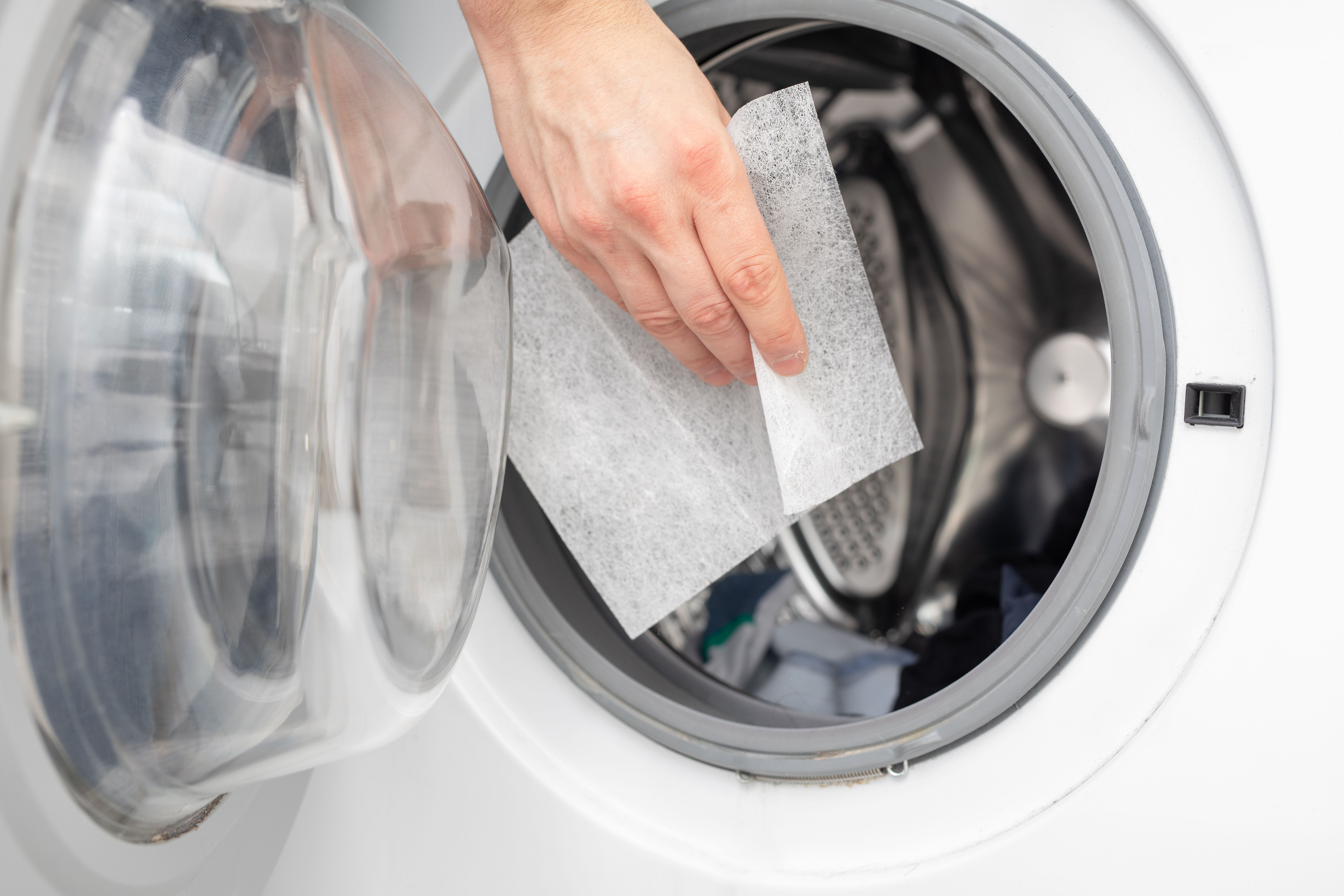 A woman throwing dryer sheets into a washing machine | Source: Getty Images