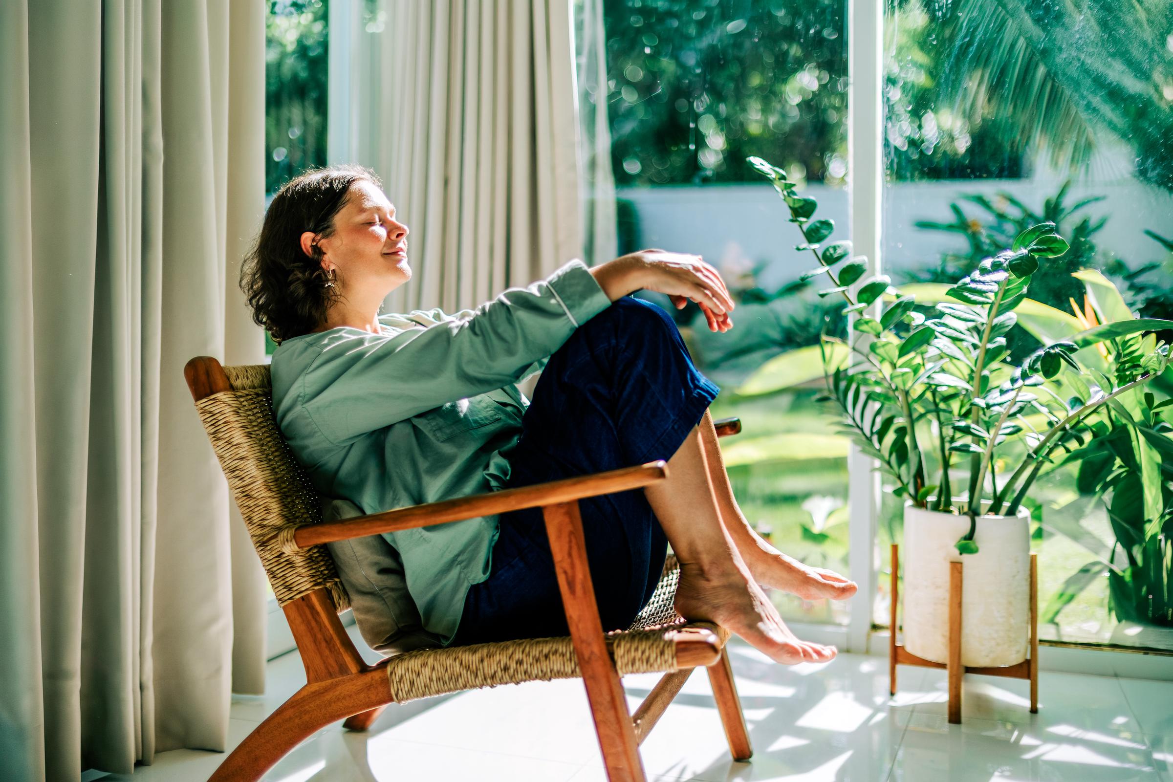 A woman relaxing in an armchair by a window, enjoying morning sun | Source: Getty Images