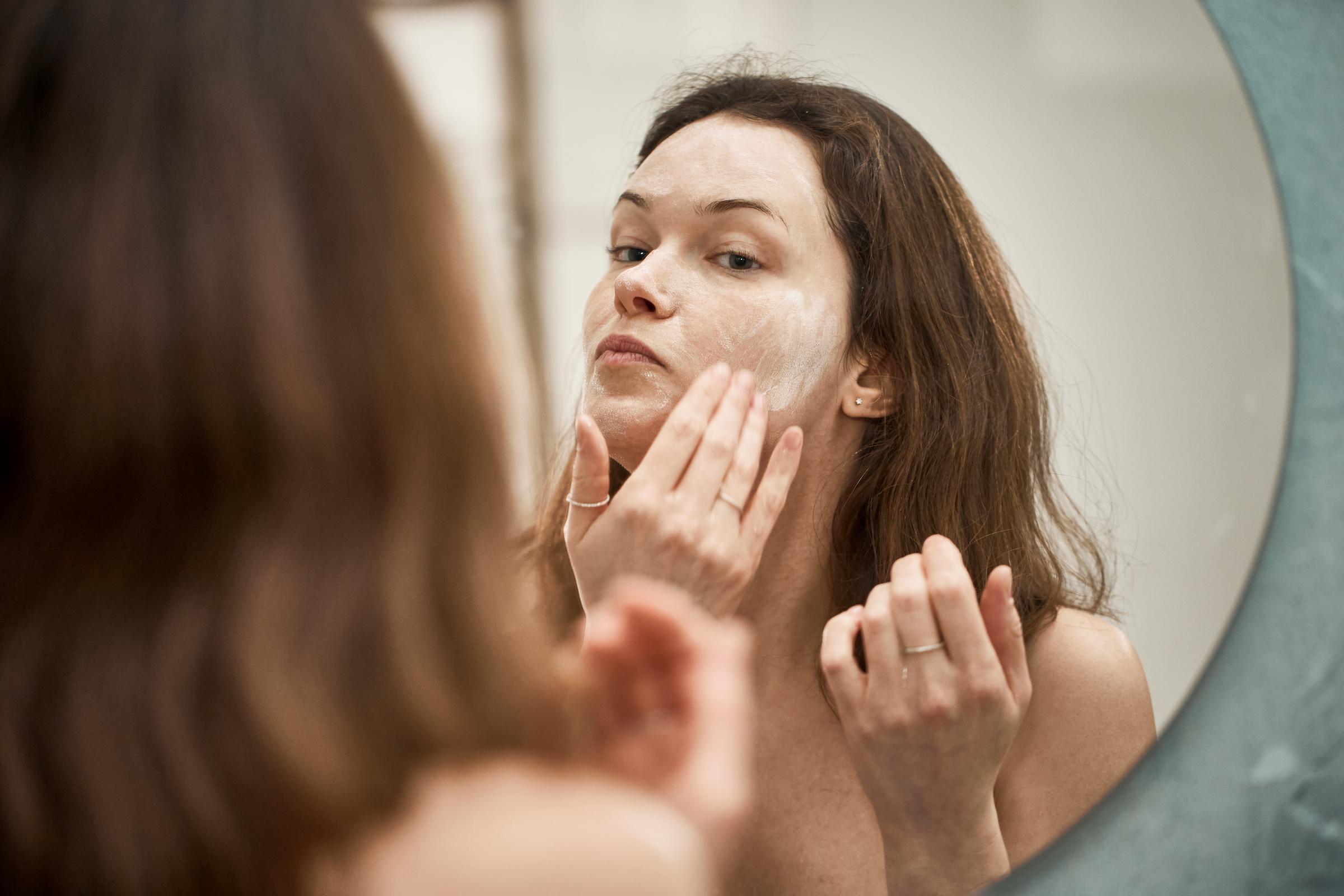 A woman applying cleanser to her face | Source: Getty Images
