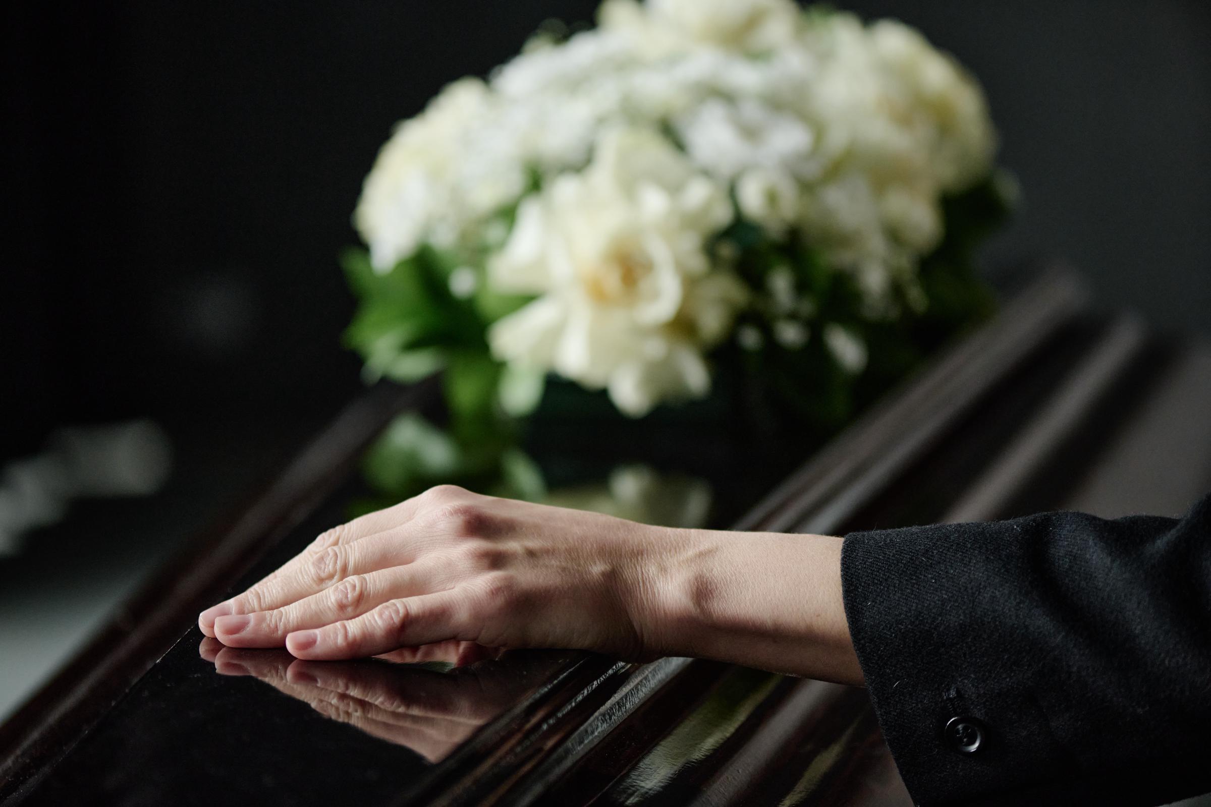 A woman's hand on a coffin | Source: Shutterstock