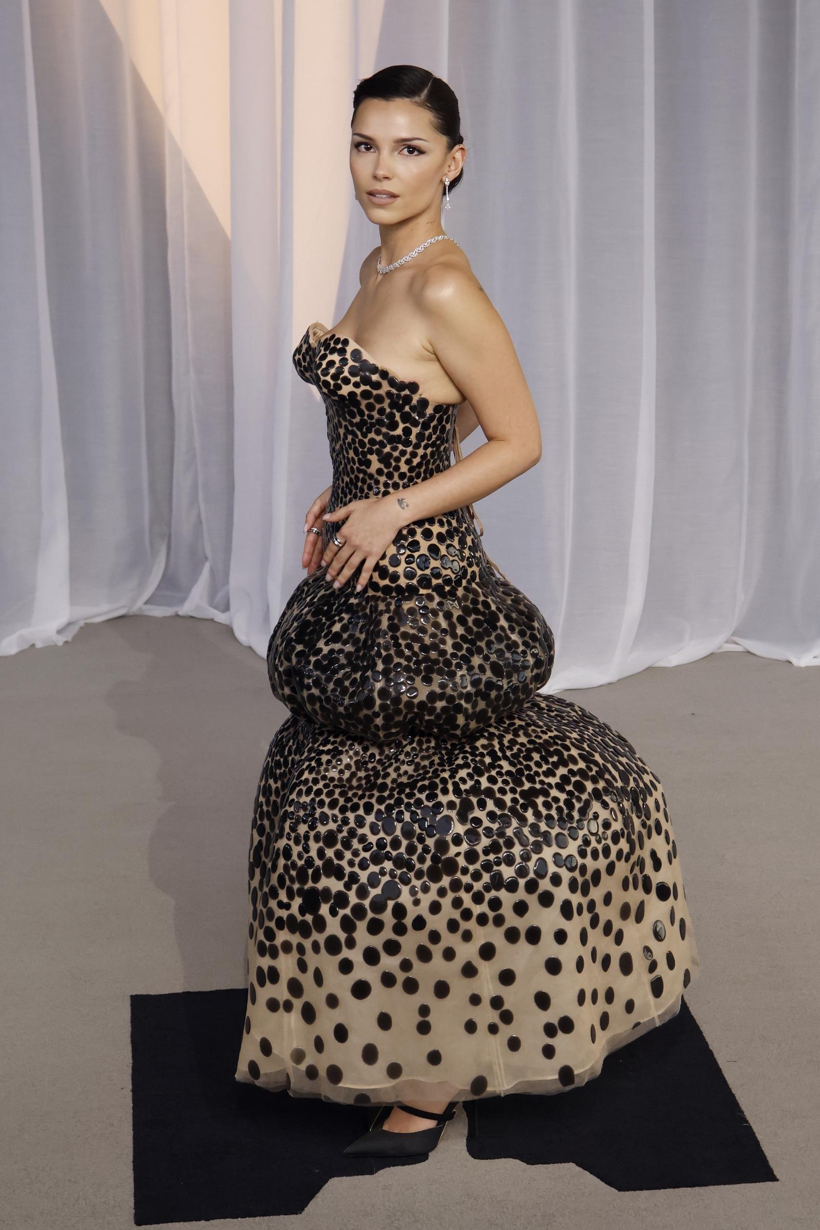Turning to reveal another angle, Navarrette shows the gown's dramatic sculptural construction, including its voluminous tiered skirt and lace-up detailing at the back.
