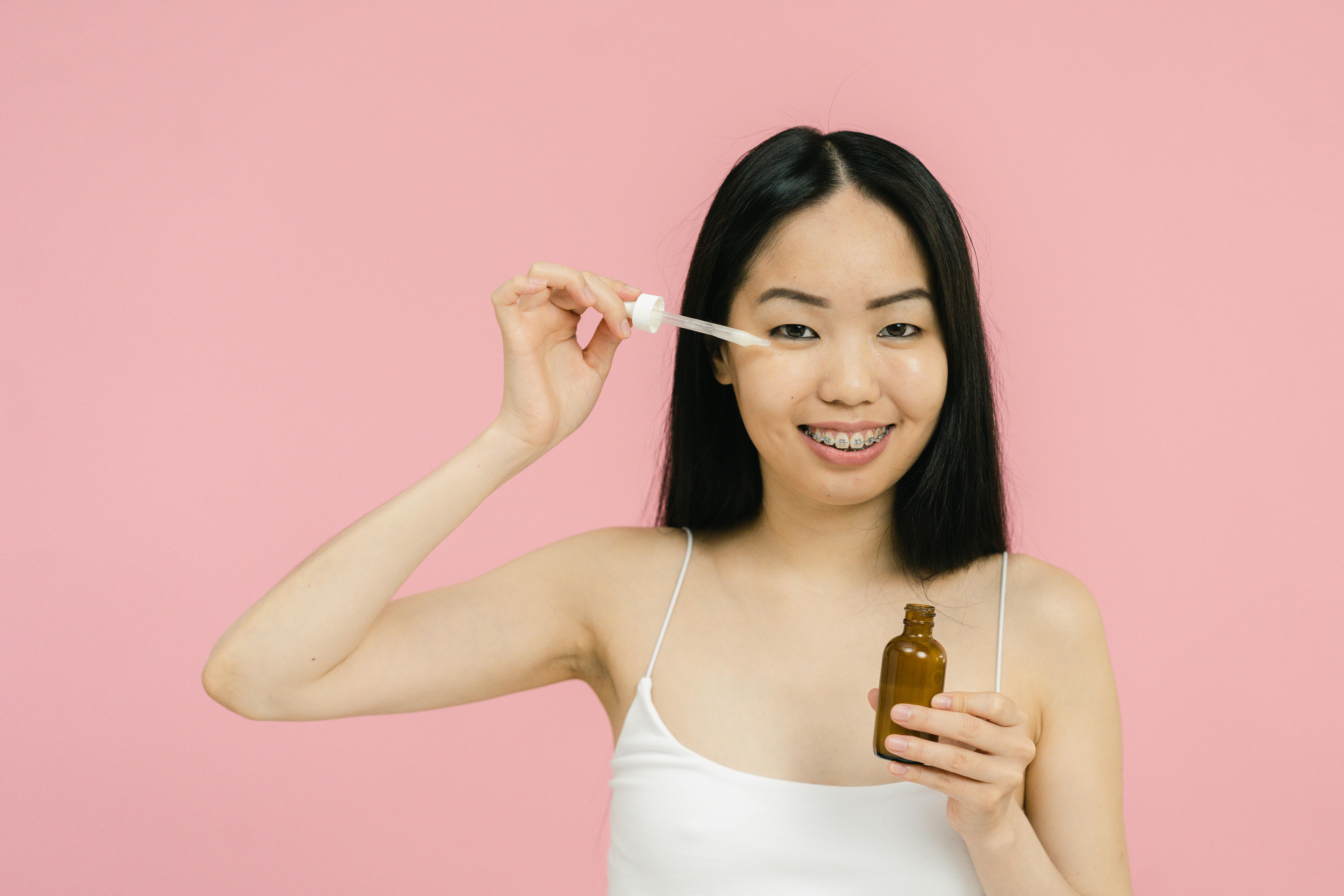 A woman applying serum on her face | Source: Pexels