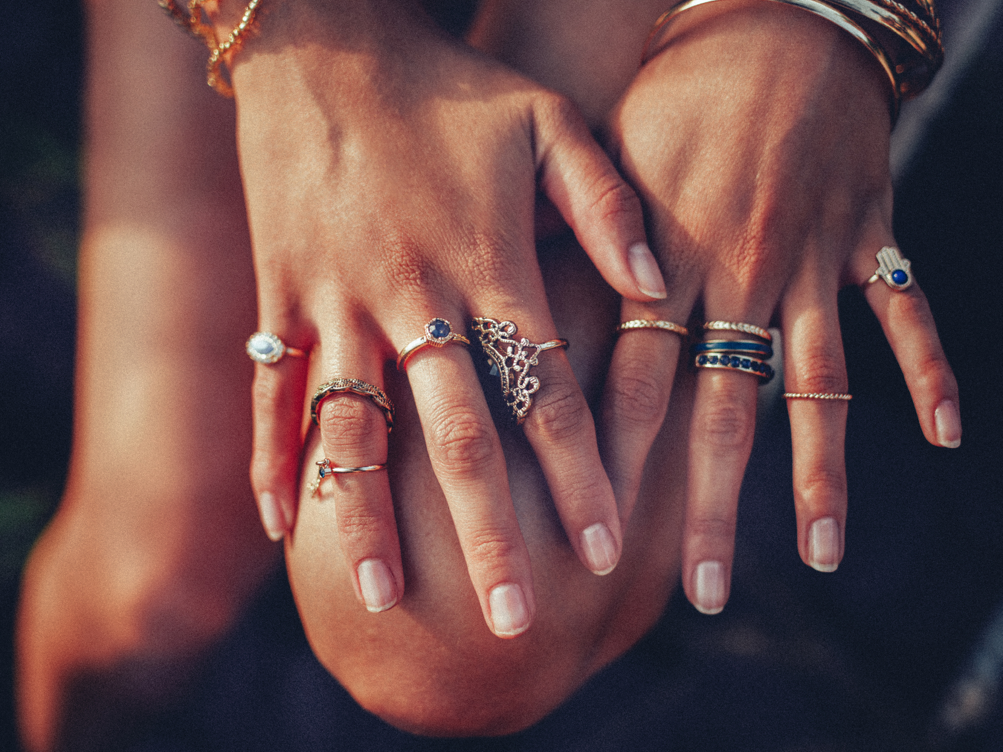 A closeup of a woman's hands with many rings on her finger, in gold and silver with dark blue stones. | Source: Getty Images