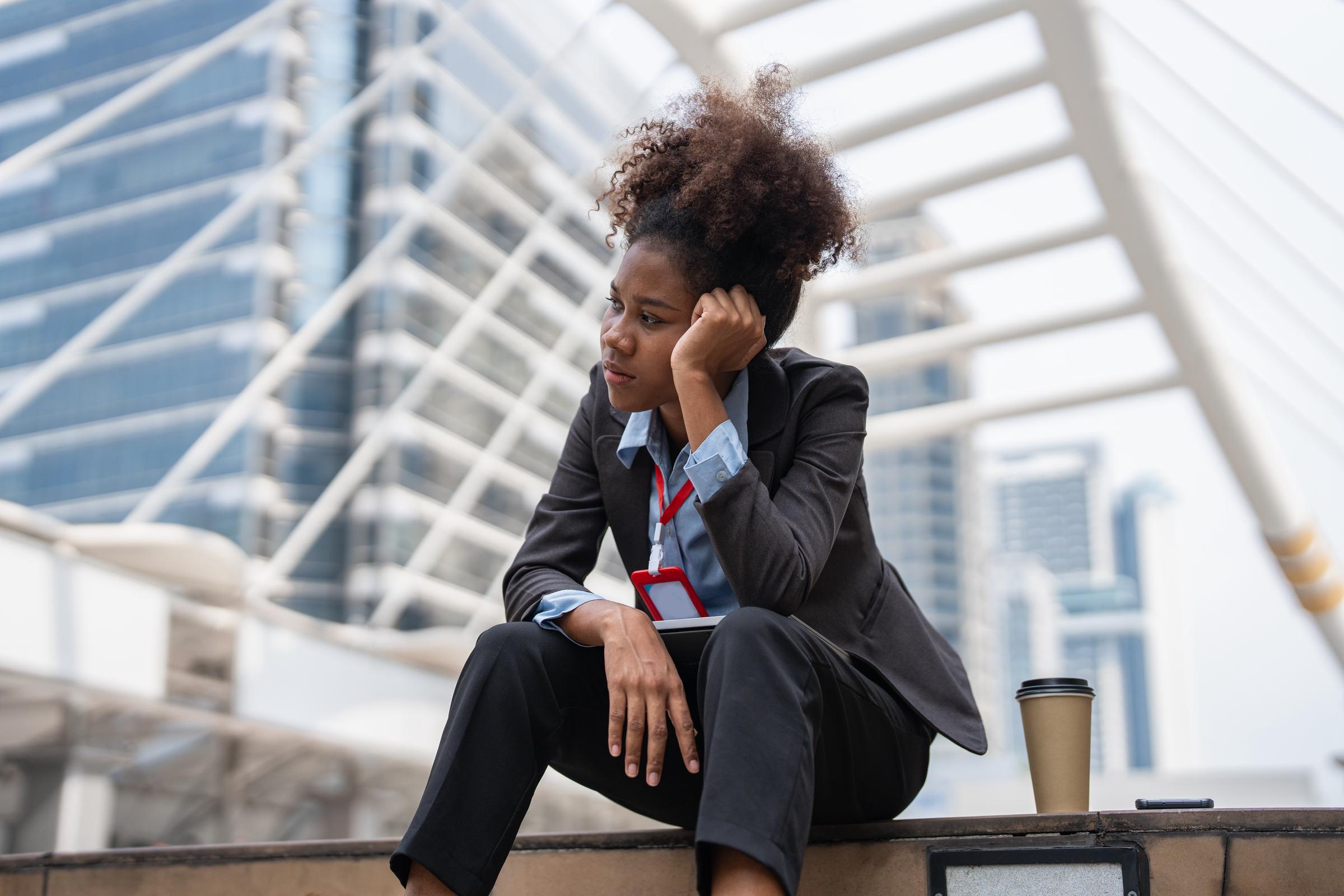A businesswoman sitting on the steps with her coffee, thinking | Source: Getty Images