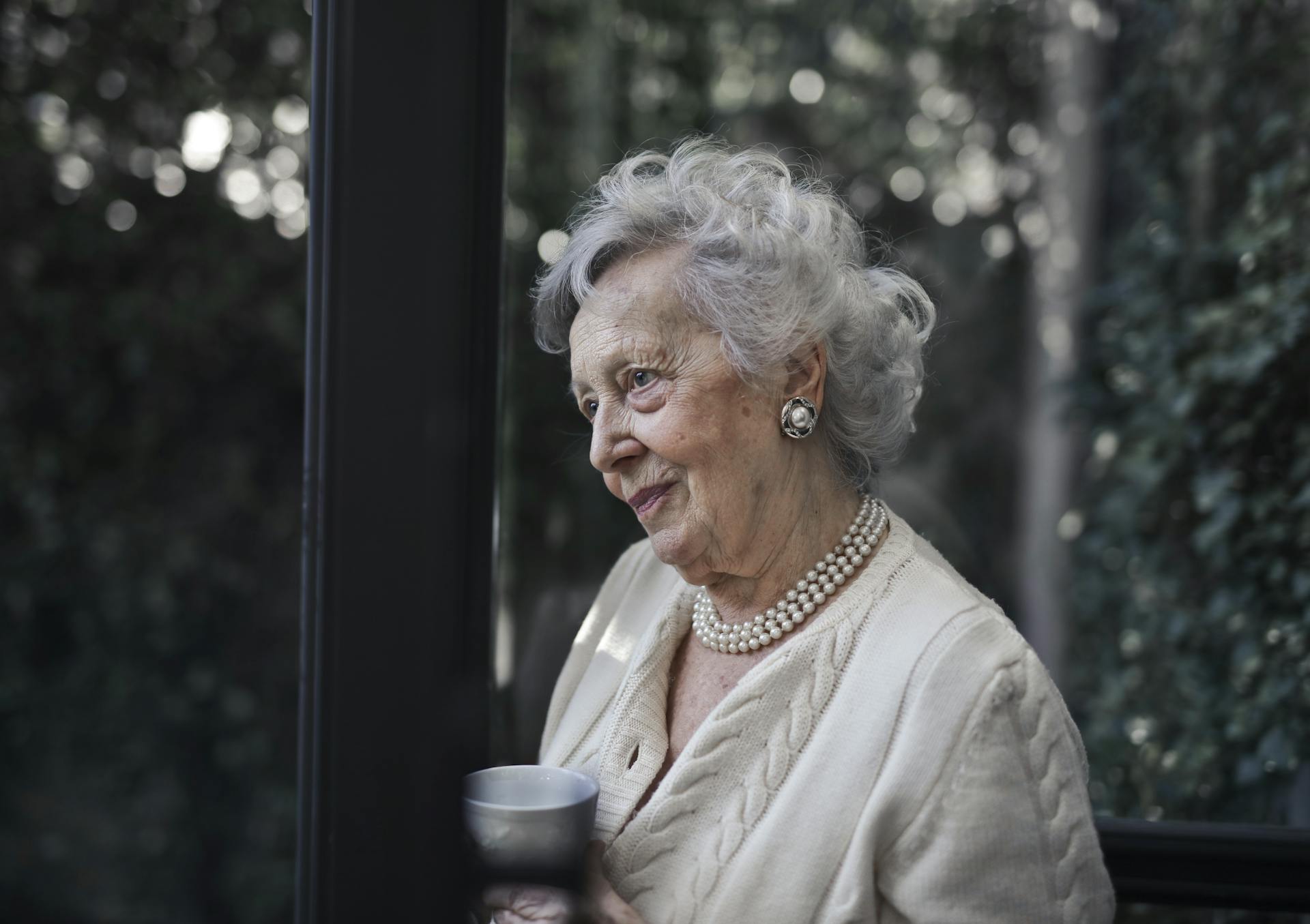 An elderly woman talking to someone while holding a cup of coffee | Source: Pexels