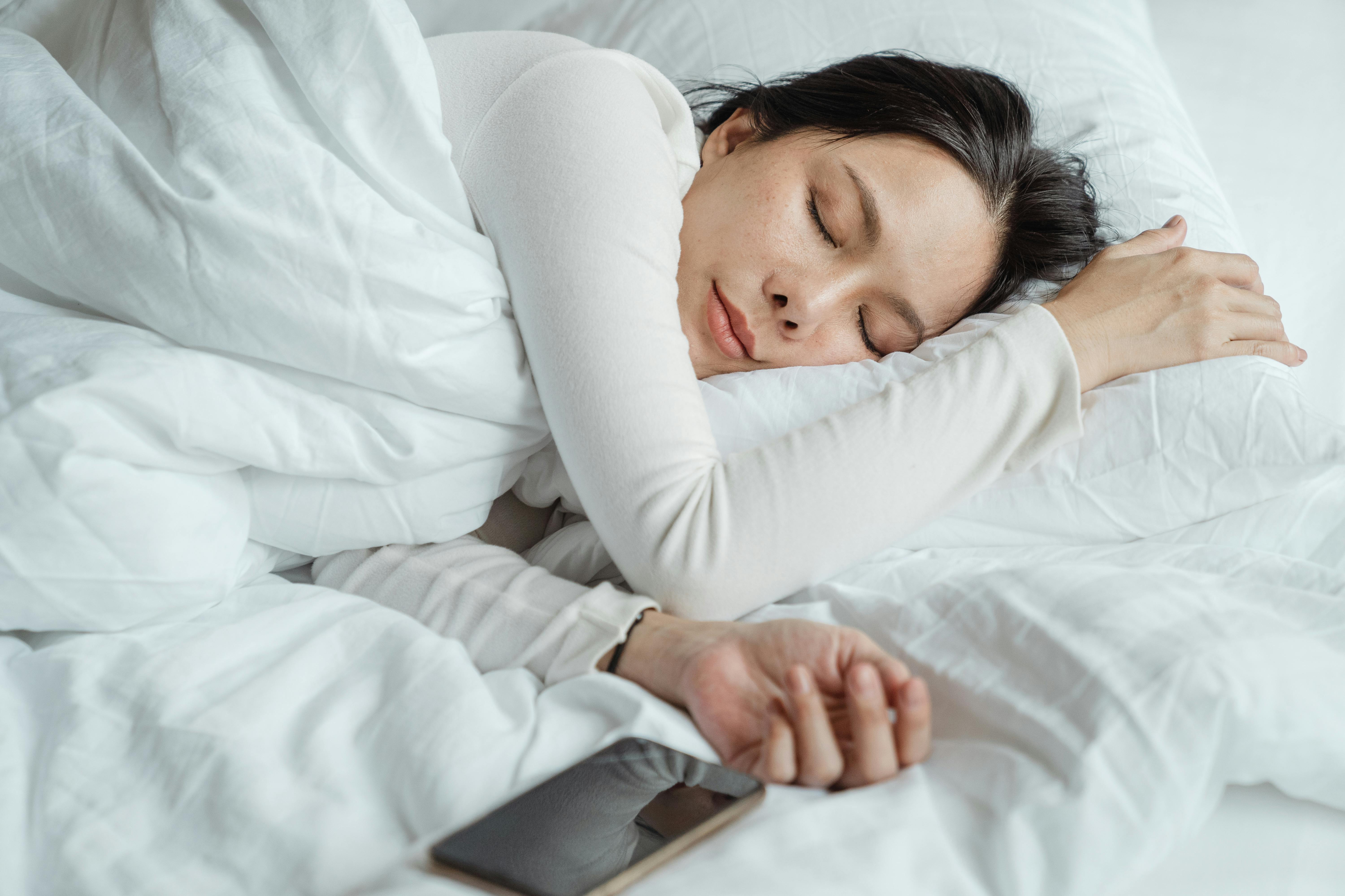 A woman sleeping beside her phone | Source: Pexels