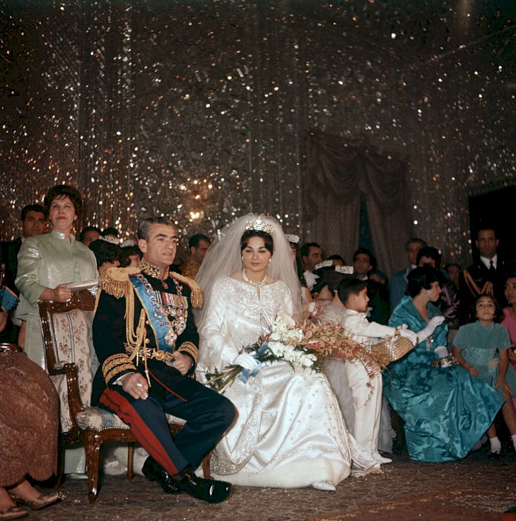Mohammad Reza Pahlavi, Shah of Iran, is seated next to her third wife Farah Diba on the day of their marriage; her gown is by Yves St Laurent and on her head a Noor-ol-Ain Diamond tiara. Iran, 21st December 1959. (Photo by Mondadori Portfolio by Getty Images)