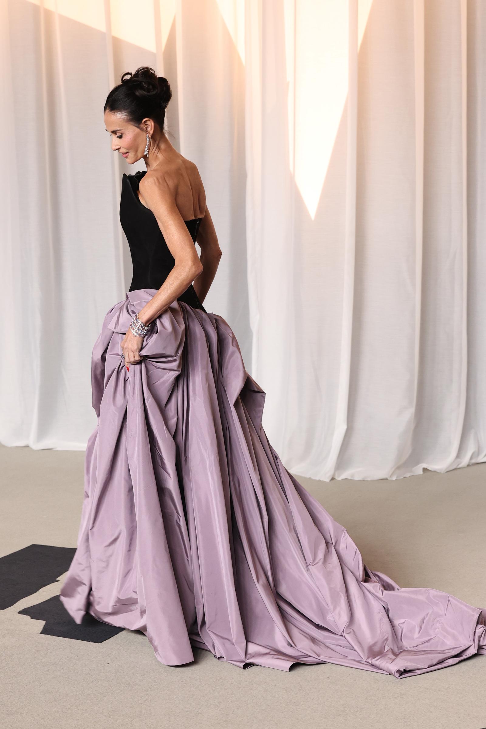 Seen from the side, Moore shows the gown's strapless back and cascading lavender skirt as its long train trails behind her.