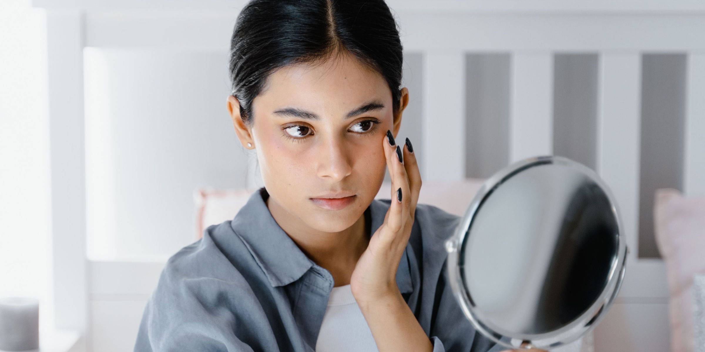 Woman observing her face through a mirror | Source: Pexels