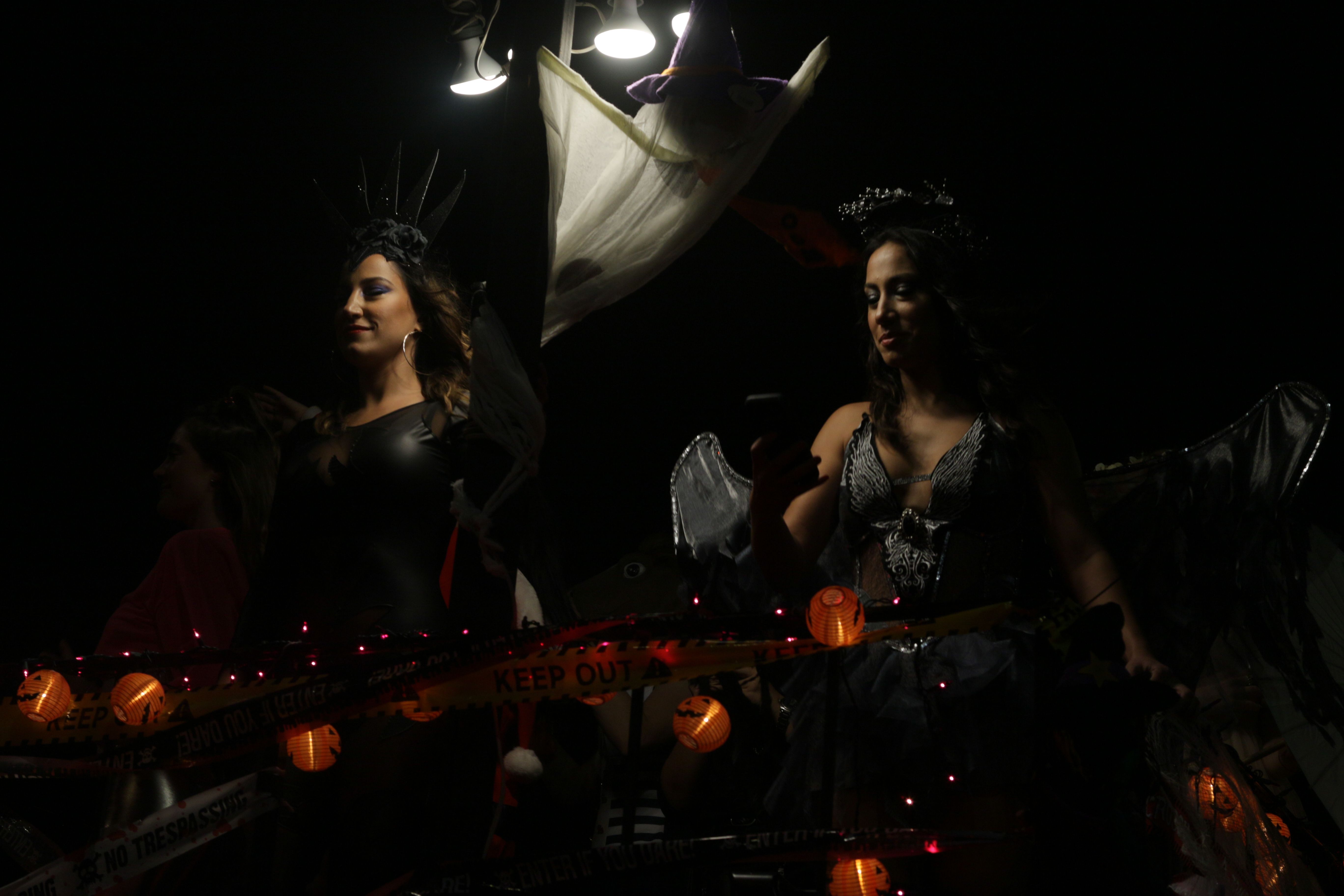 Women dressed in Halloween costumes take part in a lively nighttime parade, showcasing festive decorations | Source: Pexels