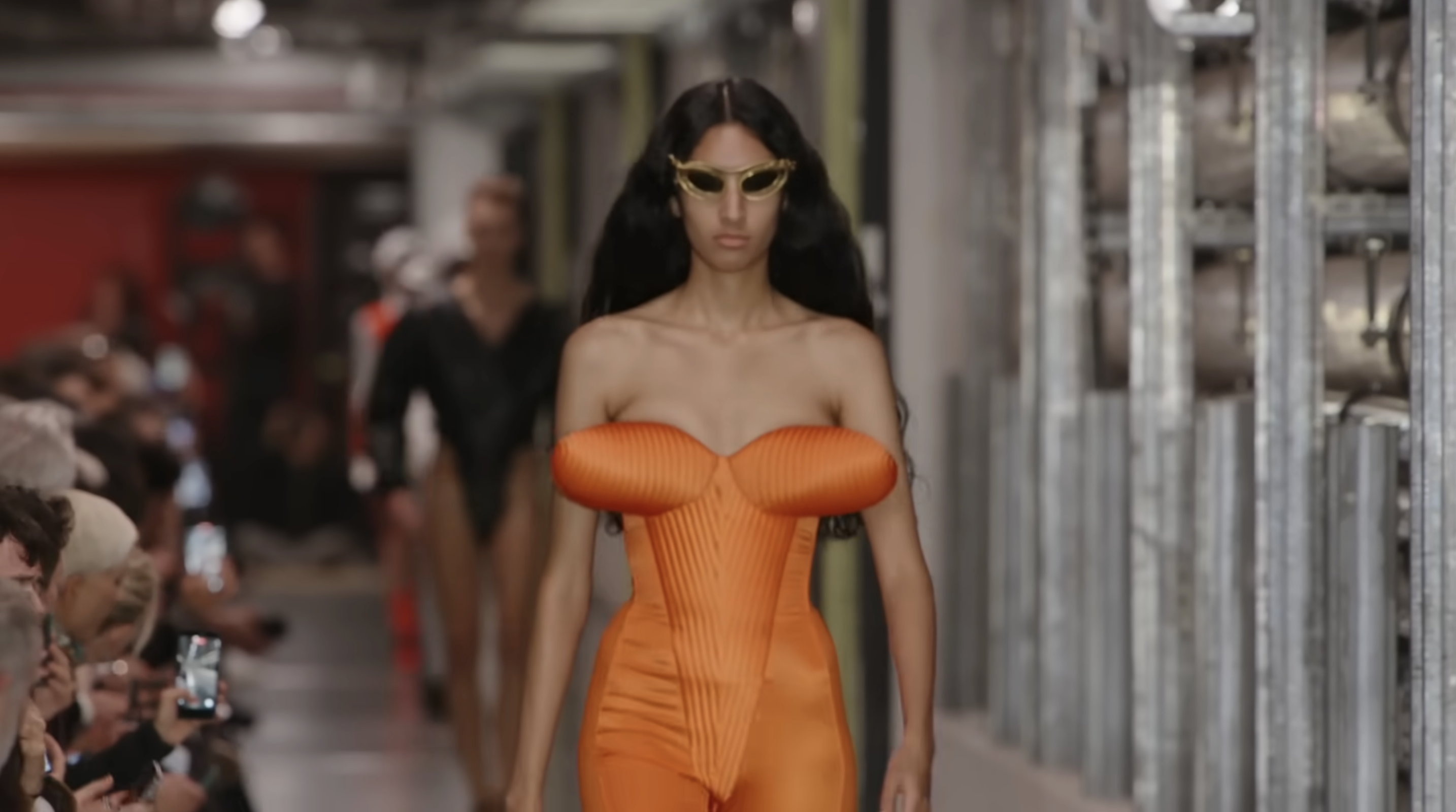 Duran Lantink opened the Jean Paul Gaultier futuristic debut ready-to-wear spring-summer 2026 collection with pneumatic silhouettes. This orange look features a cone bra design within a uniquely structured jumpsuit. From a post dated October 5, 2025. Source: Youtube/@jeanpaulgaultier