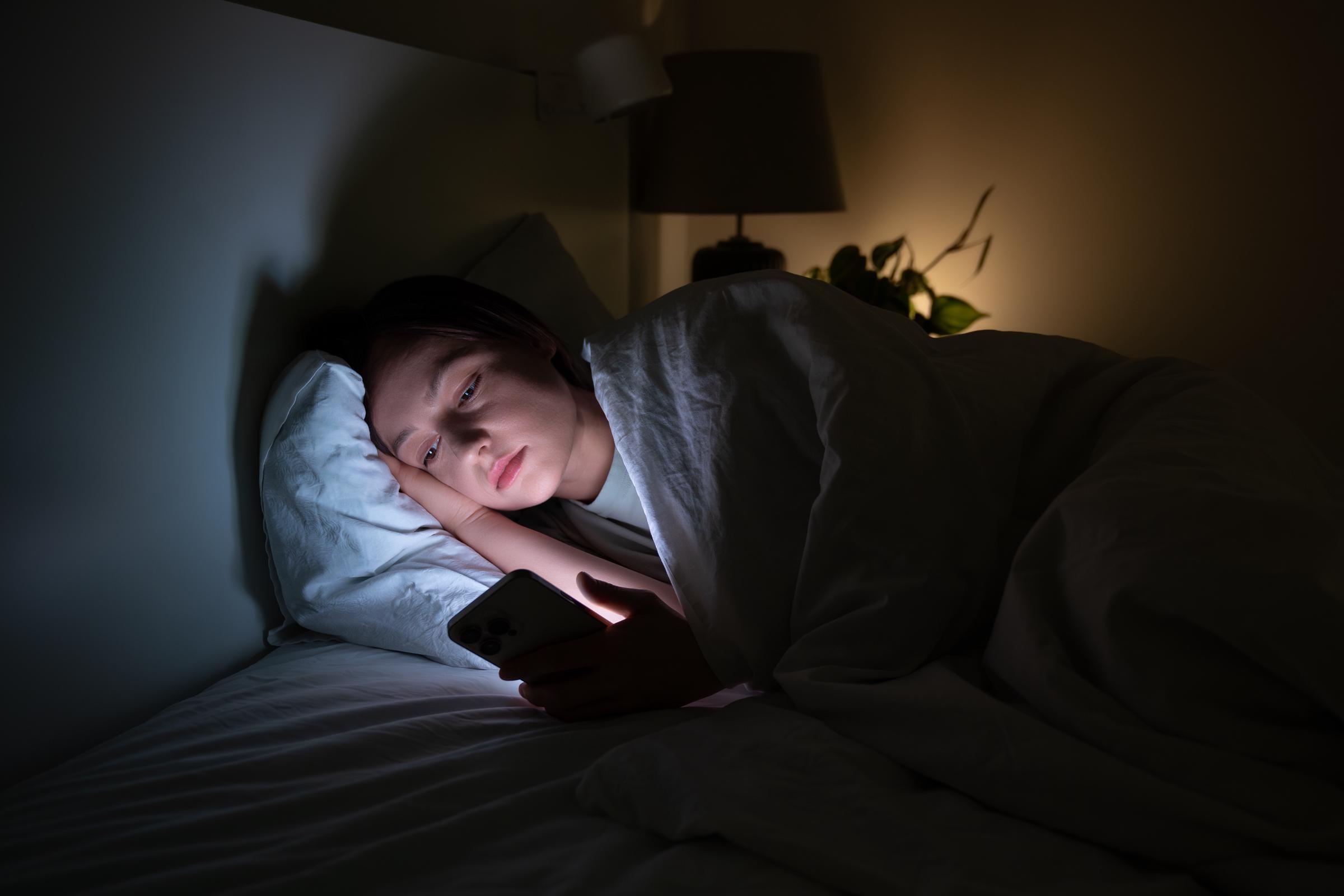 A woman scrolling on her phone while in bed | Source: Getty Images