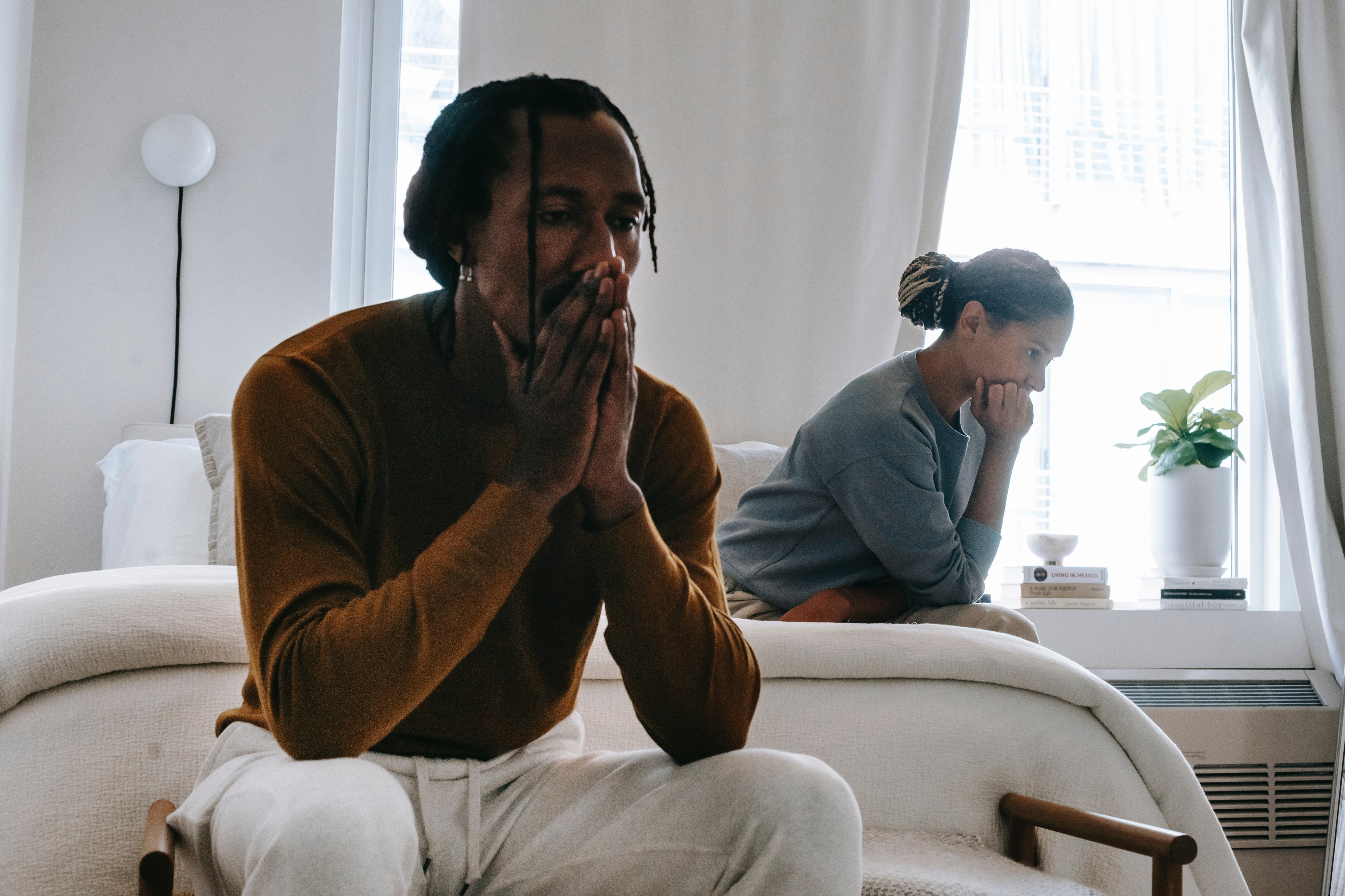 An unhappy couple sitting on the bed after having an argument | Source: Pexels 