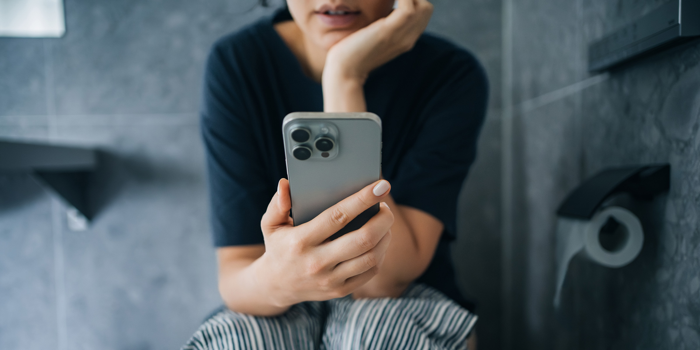 A woman scrolling on her phone while sitting on the toilet | Source: Getty Images