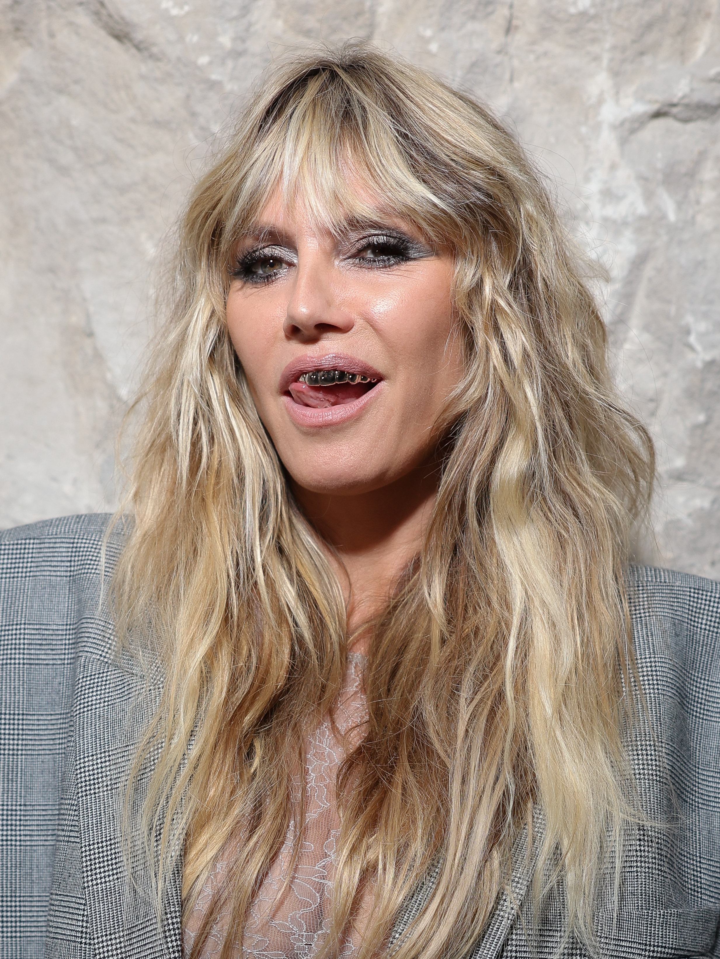 Heidi Klum completed her bold look with striking silver smoky eye makeup and edgy silver grills, adding a fun and daring edge to her ensemble.