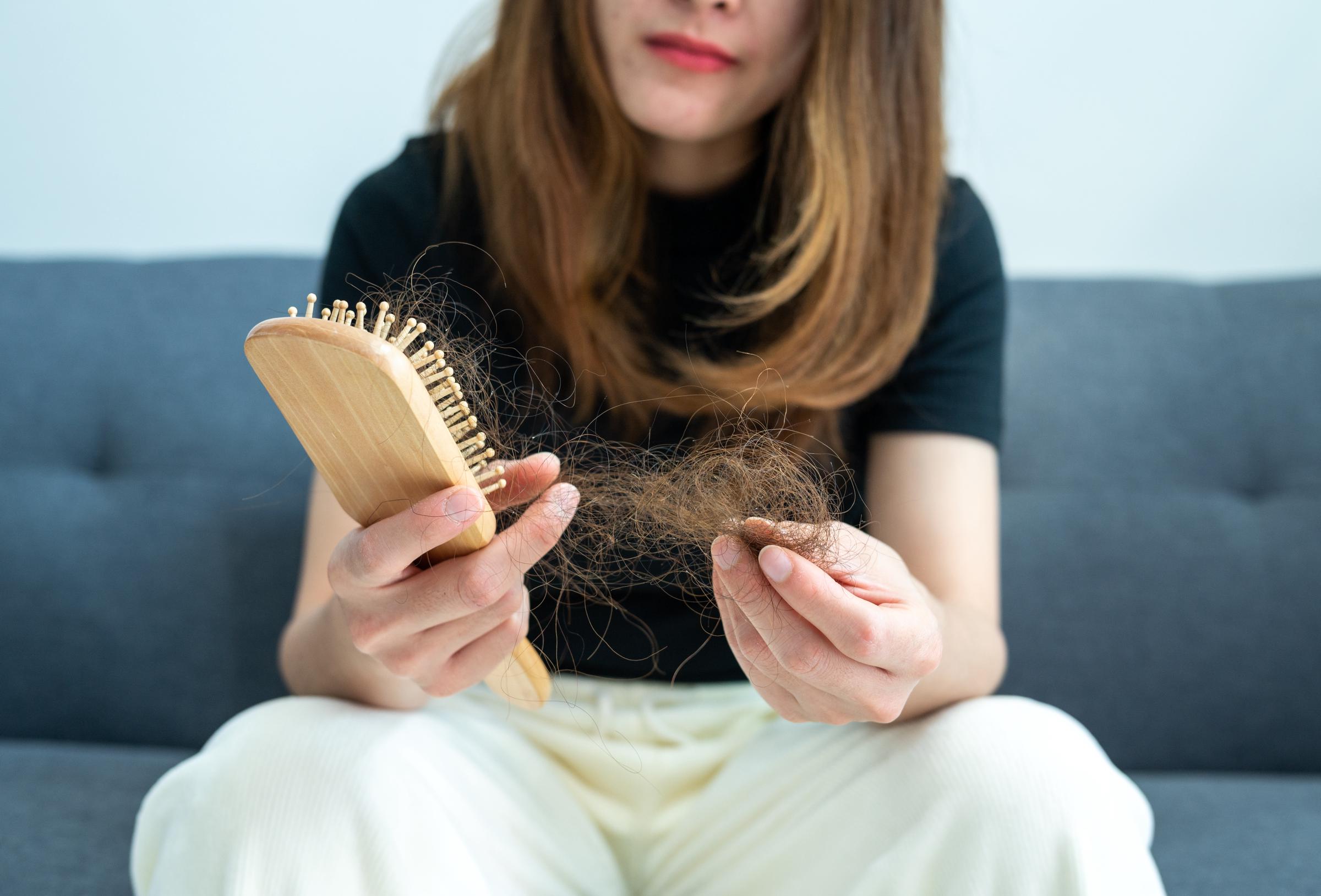 A woman holding a brush and a clump of hair | Source: Getty Images