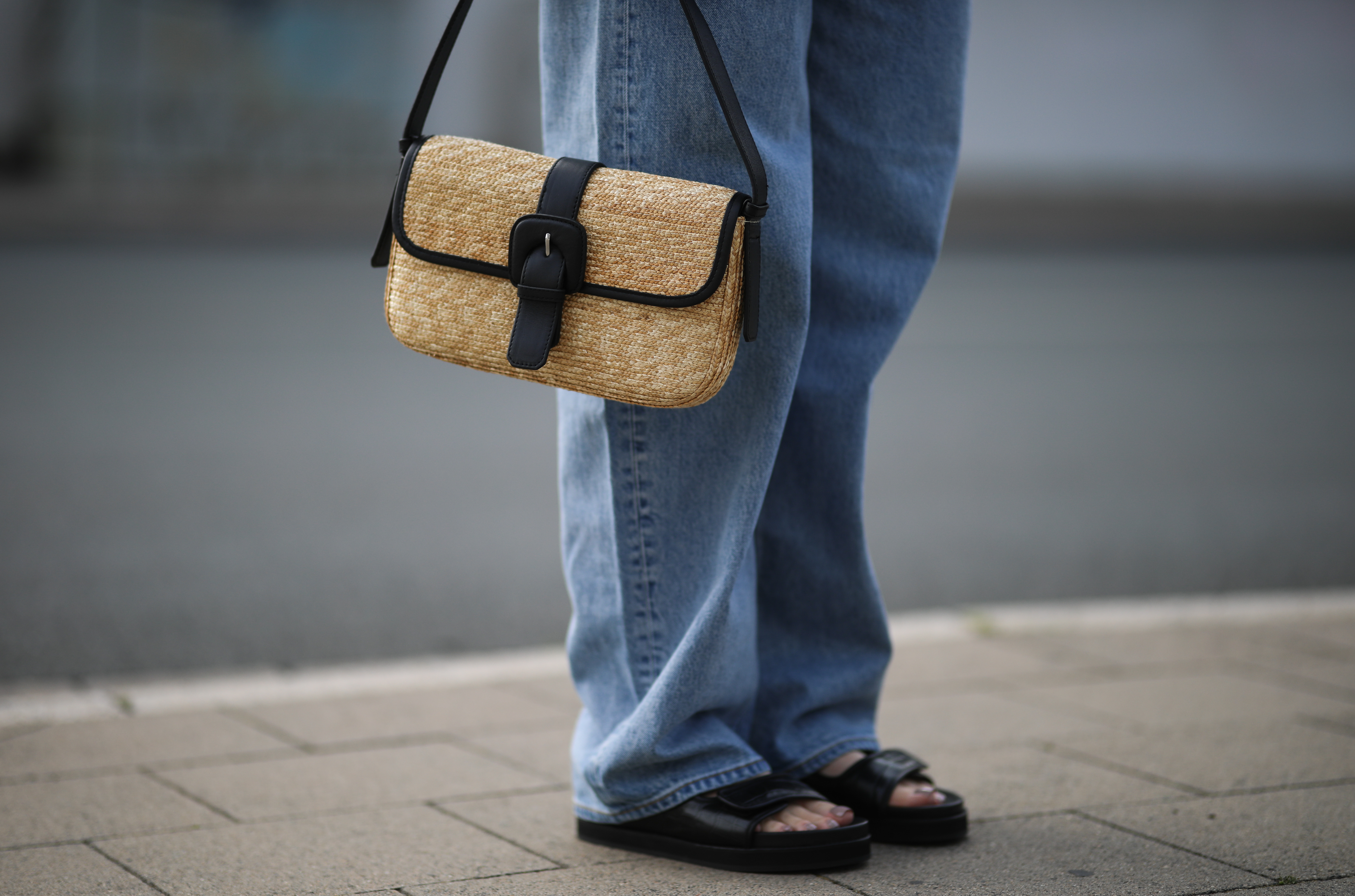 Jeans paired with black leather dad sandals and a straw baguette bag on August 15, 2020, in Germany | Source: Getty Images