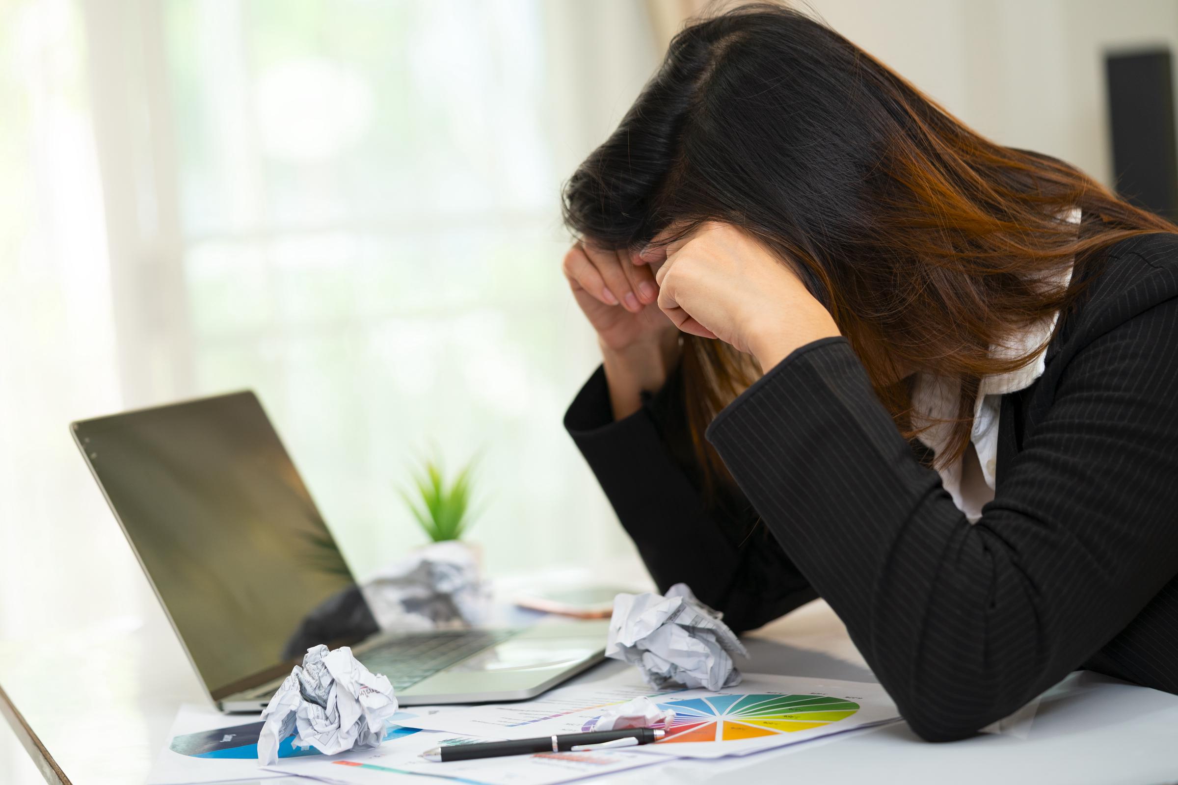 A frustrated woman sitting at her cluttered work desk | Source: Getty Images