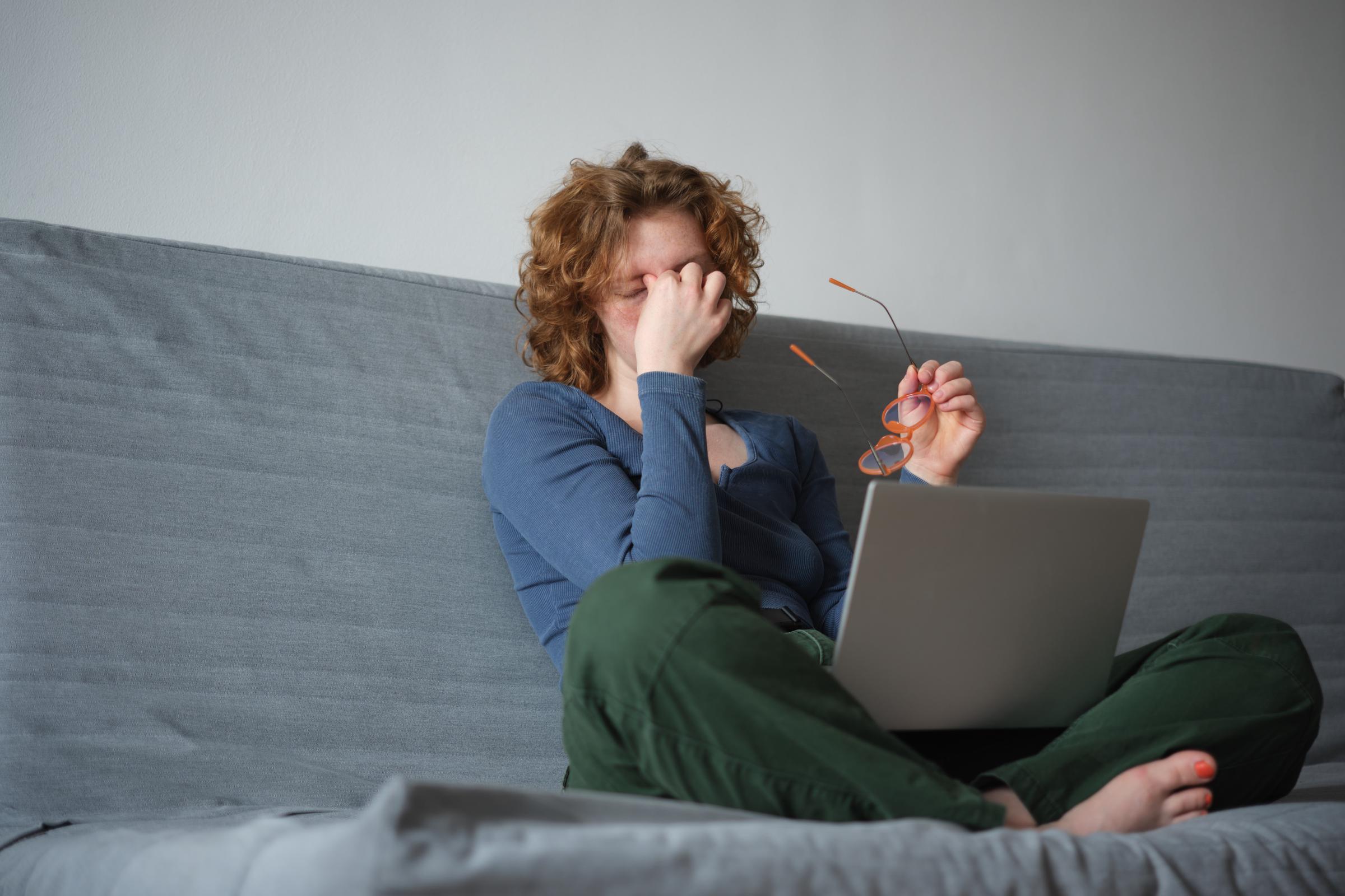A tired woman pinching the brudge of her nose in exhaustion | Source: Getty Images