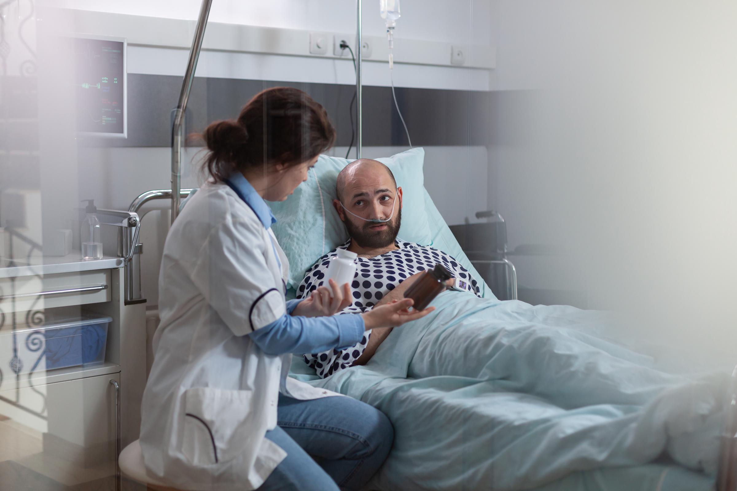 Sick man with a nasal oxygen tube resting in bed during a medical examination | Source: Magnific