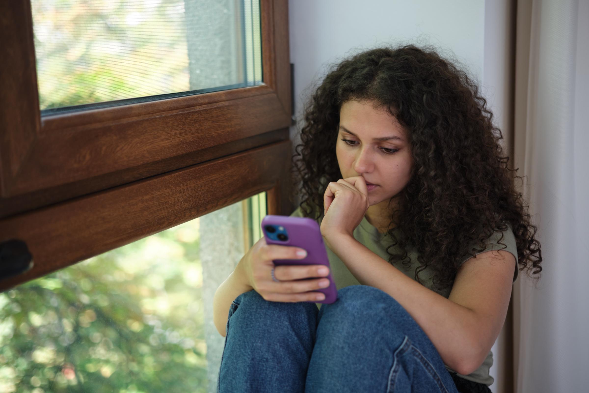 A young woman scrolling on her phone | Source: Getty Images