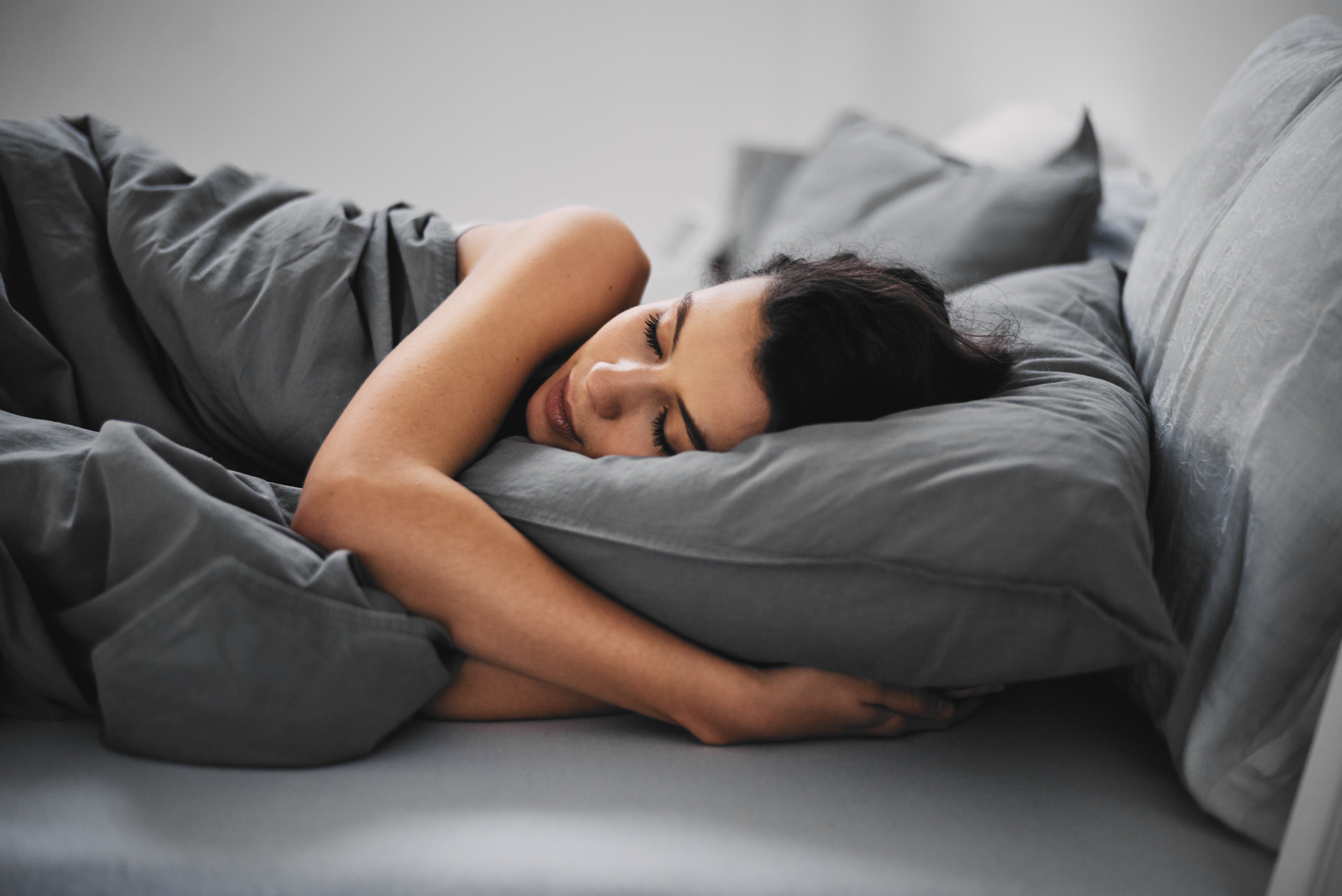 Woman sleeping on cotton sheets. | Source: Getty Images