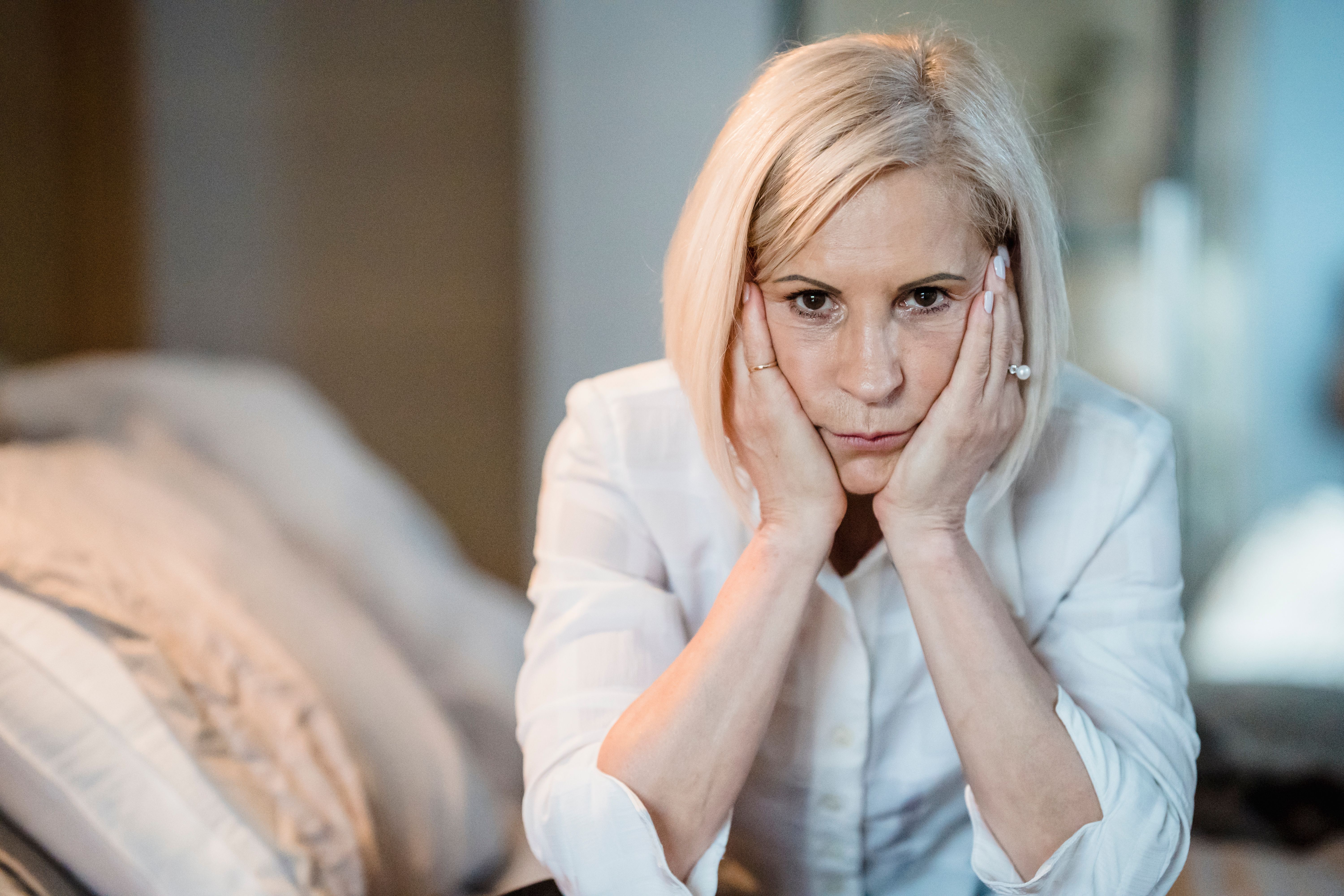 A frowning middle-aged woman holding her head by the cheeks | Source: Pexels