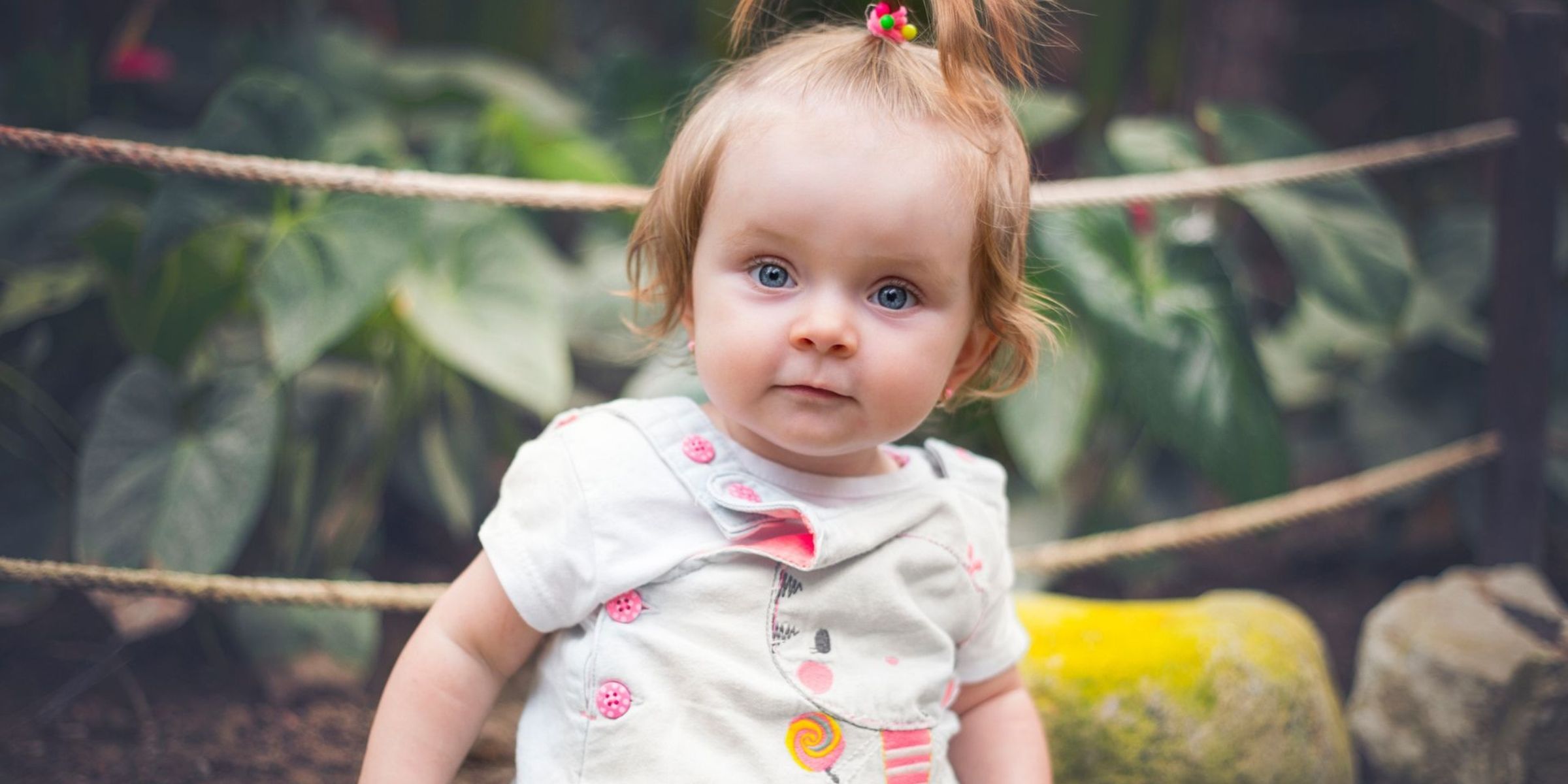 Baby girl with blue eyes and a small ponytail sitting outdoors | Source: Pexels