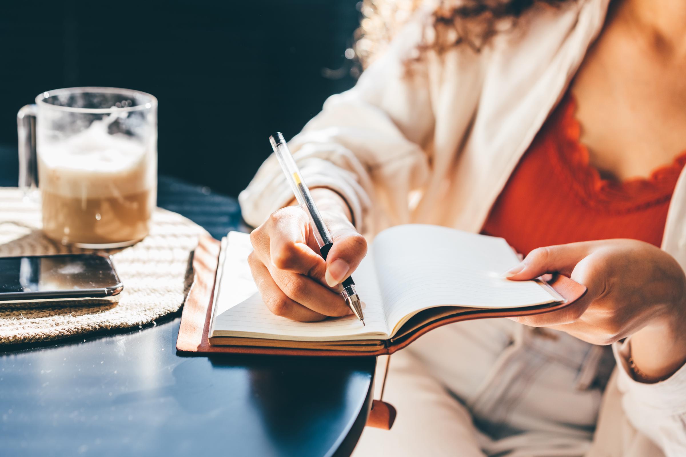 A woman journaling outside with a cup of coffee | Source: Getty Images