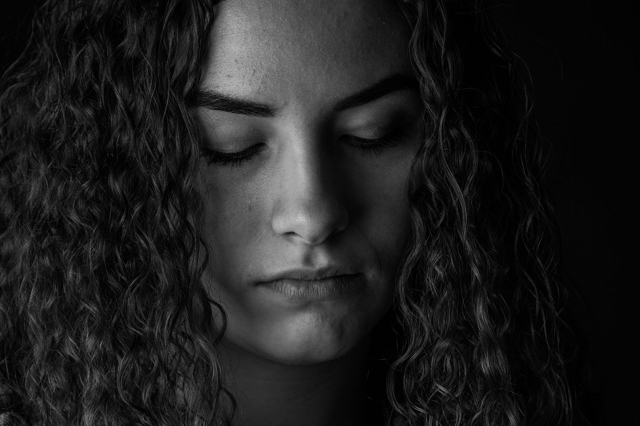 A black-and-white close-up image of a woman looking ashamed | Photo: Pixabay/Małgorzata Tomczak
