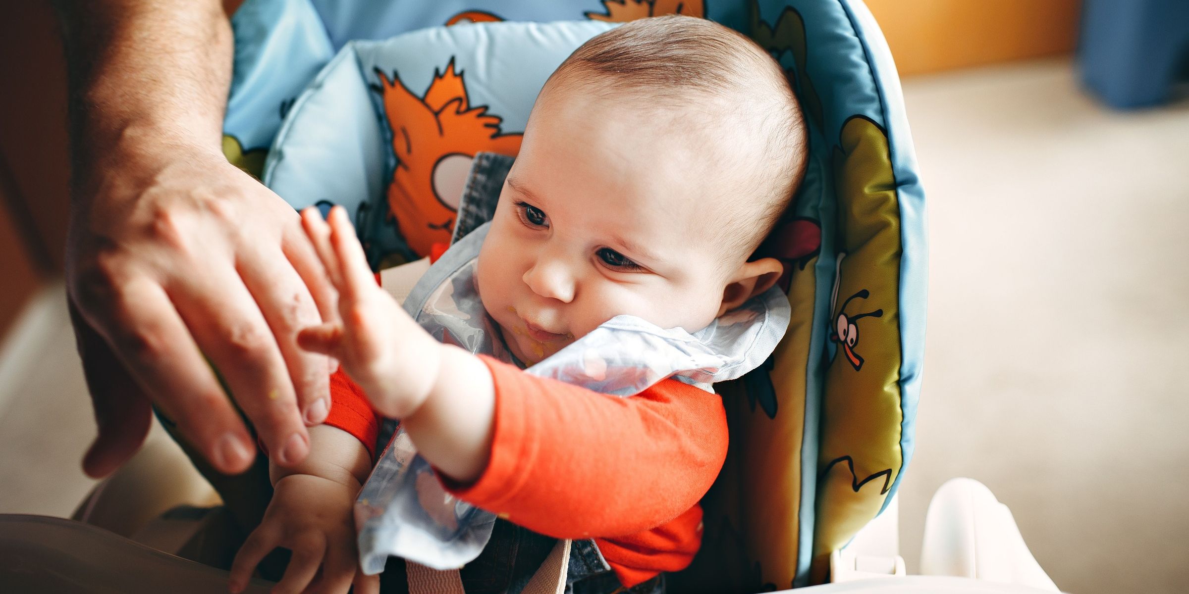 A close-up of a baby Cute baby in highchair reaching out to their parent | Source: Pexels