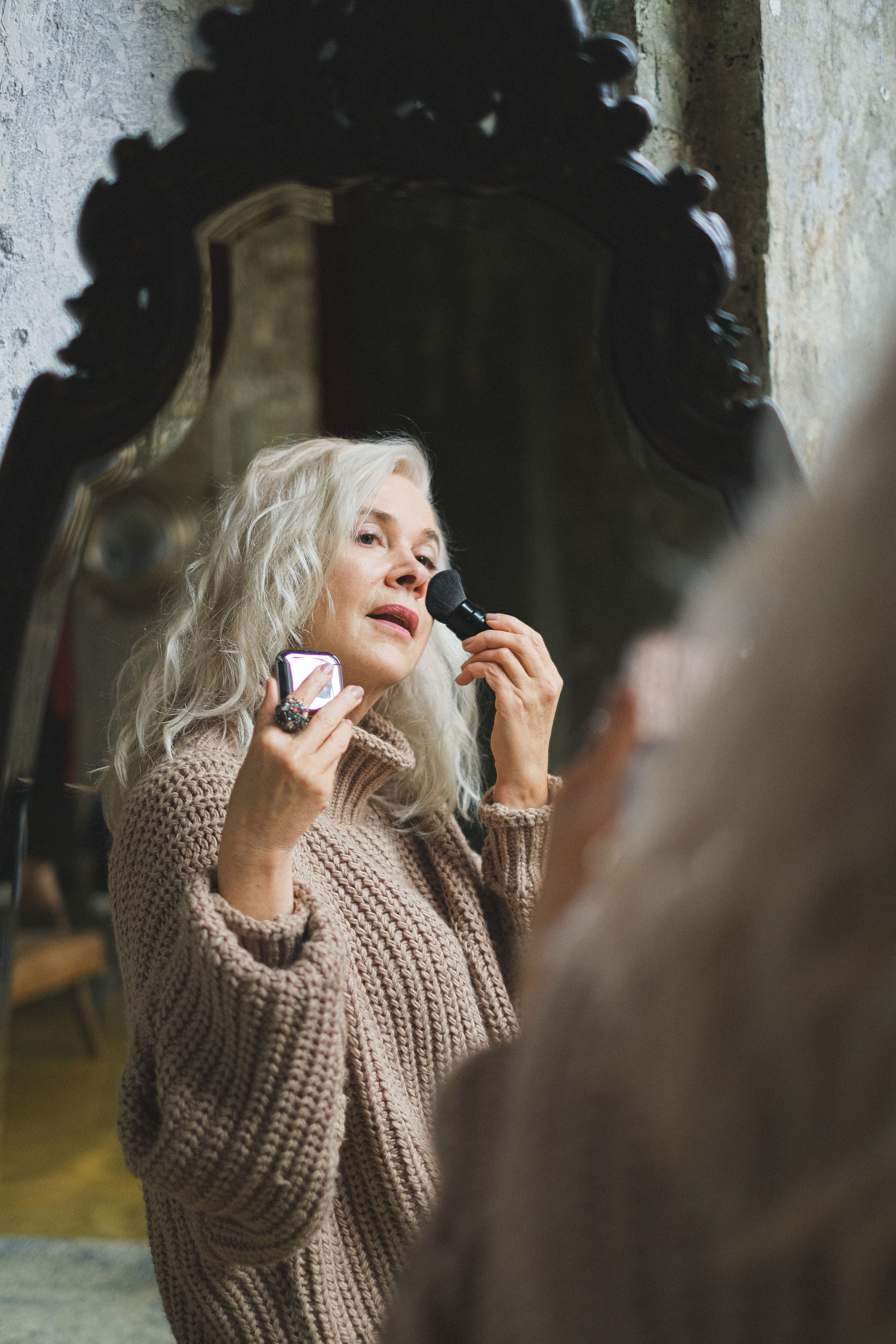 Mature woman dusting powder on her face | Source: Pexels