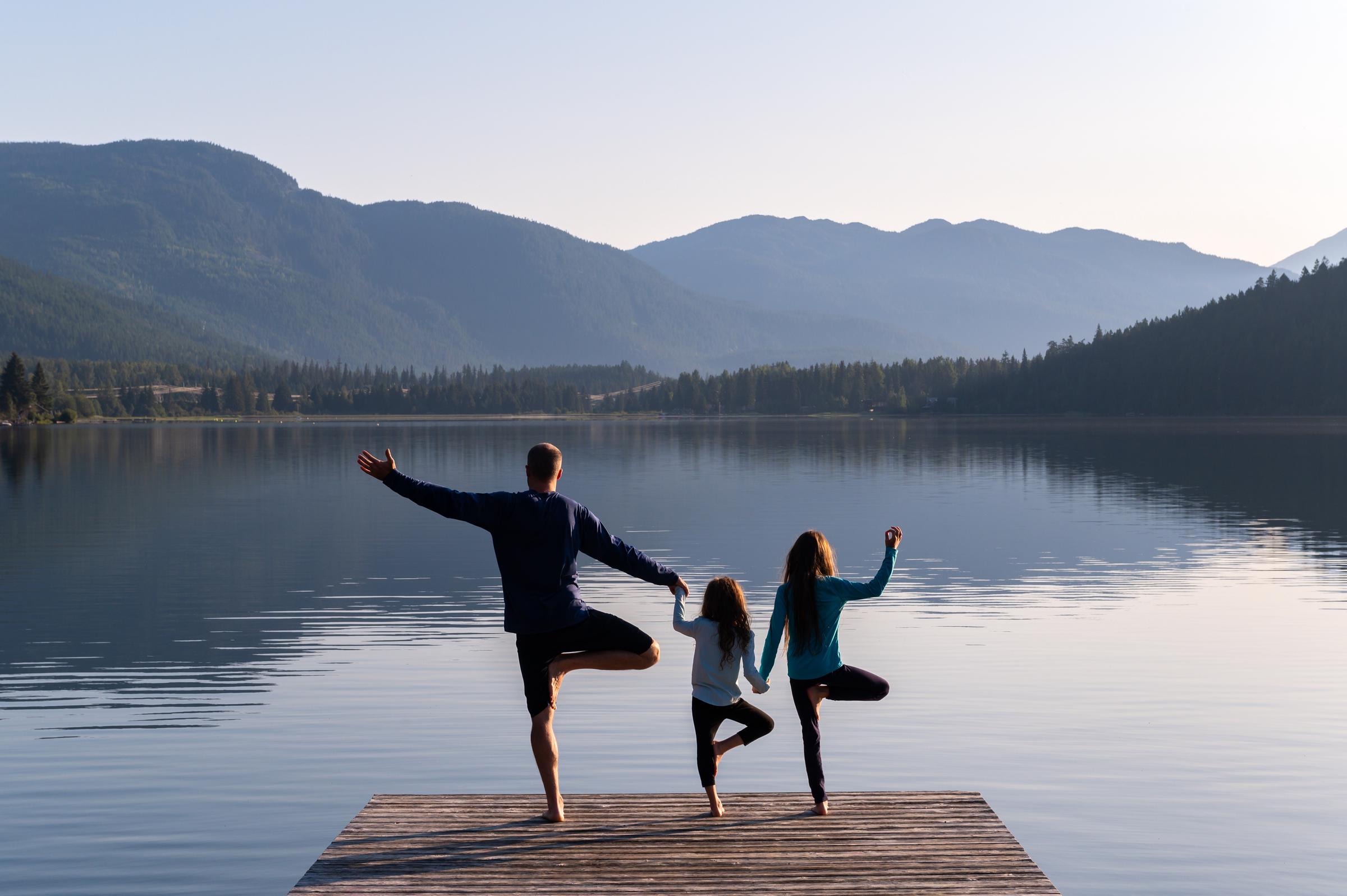 Family practicing yoga outdoors. | Source: Getty Images